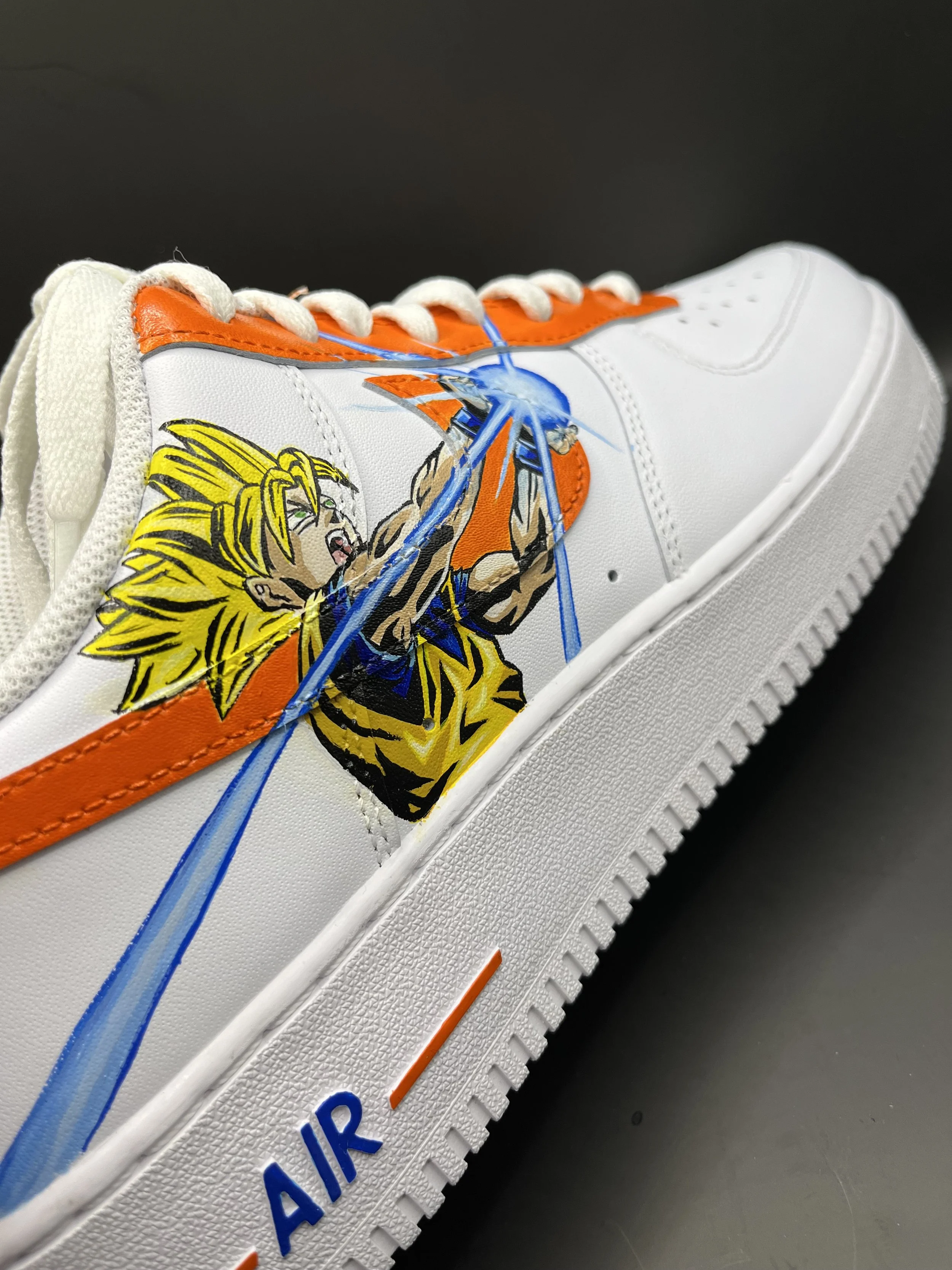 A white sneaker featuring an illustration of Goku from Dragon Ball Z, with yellow hair, performing a blue energy attack, on a black background.