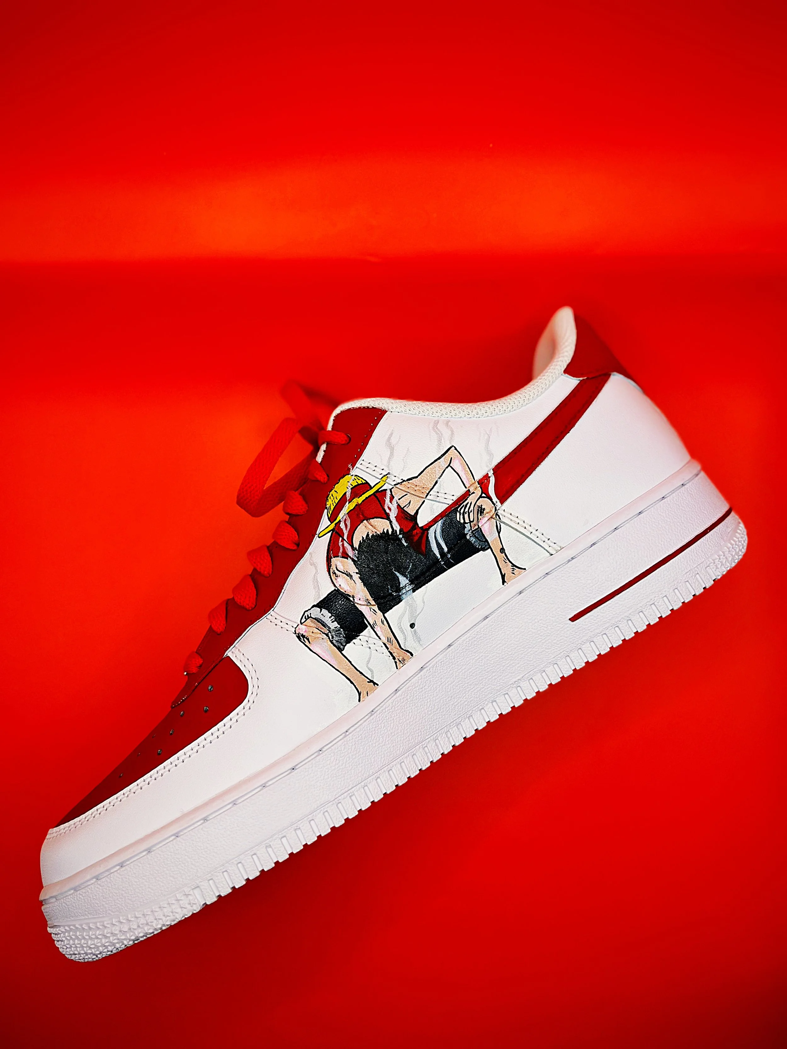 A white sneaker with red accents and a graphic print of a woman in a swimsuit, on a red background.