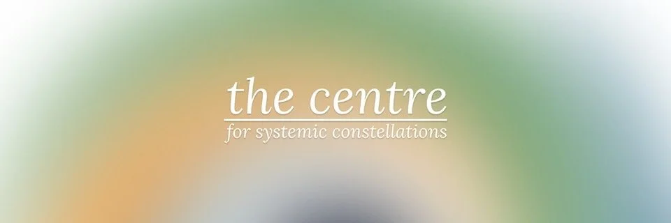A logo with the text 'the centre for systemic constellations' on a soft, abstract multicolor background.
