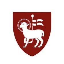 A shield with a white goat and a cross above it, and two striped flags behind the goat.