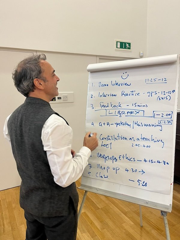 Man standing in front of a whiteboard, writing notes during a presentation or teaching session in a classroom or conference room.