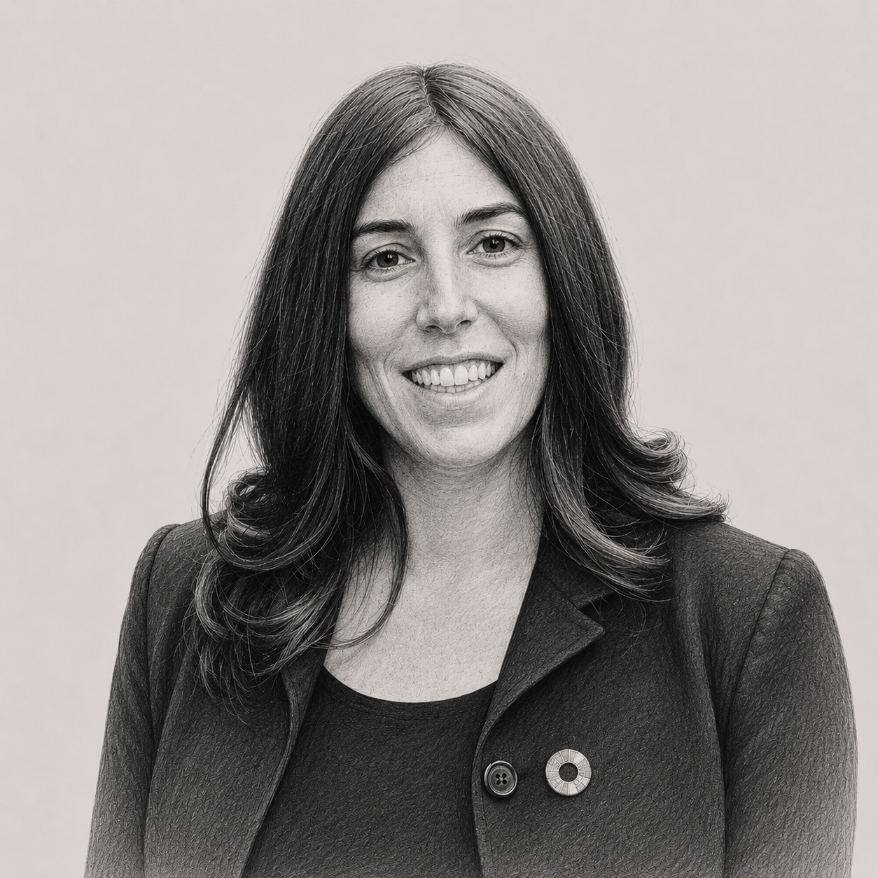Black and white photo of a smiling woman with shoulder-length dark hair, wearing a dark blazer and a top with a textured pattern, standing against a plain background.