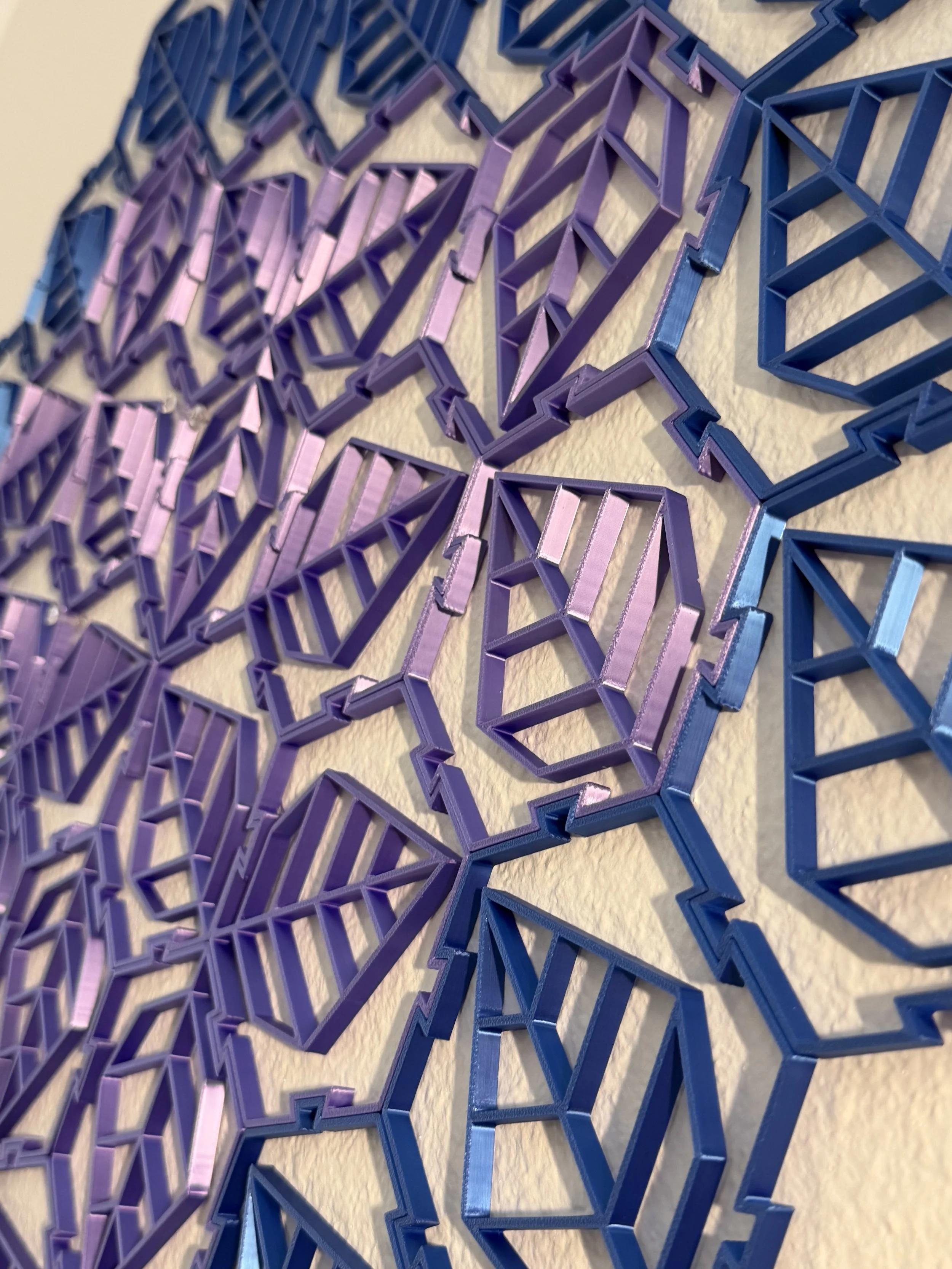 Close-up image of a colorful, geometric wall art piece with a mosaic-like pattern made from 3D plastic frames in shades of blue and purple.