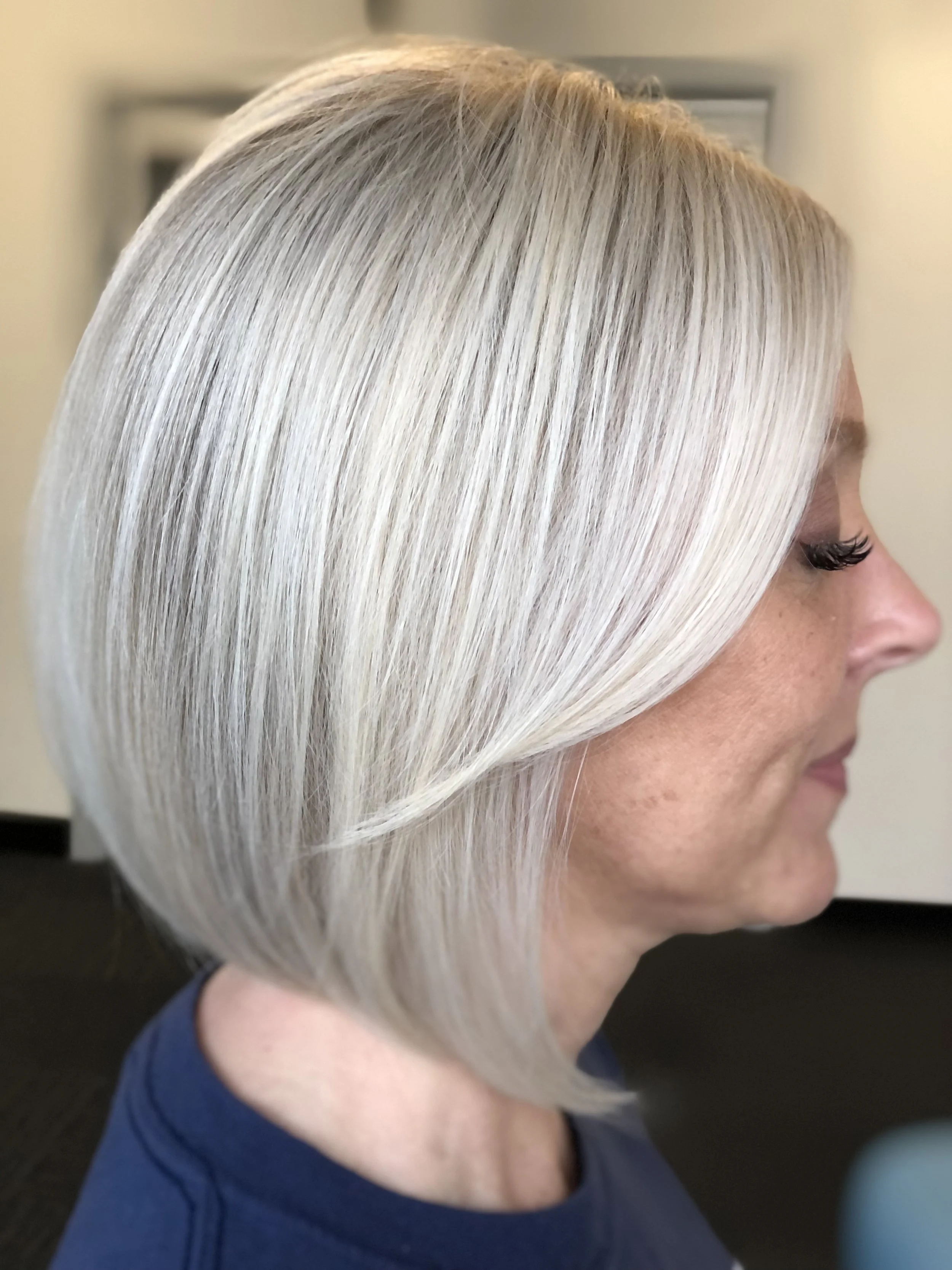 Profile of a woman with short, platinum blonde hair, wearing a dark blue top.