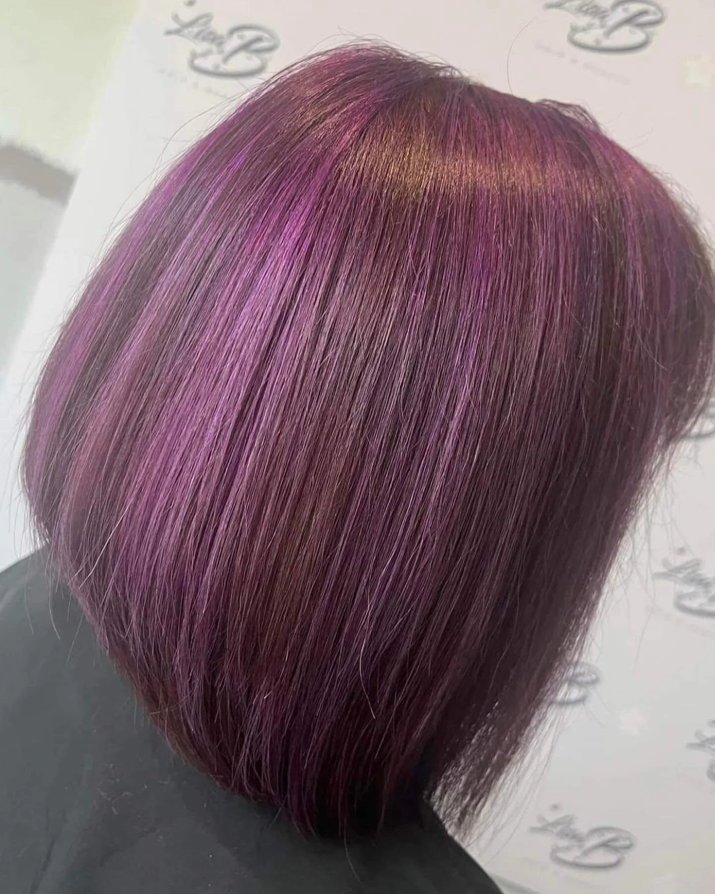 Close-up of a person’s hair dyed in a vibrant purple shade with hints of pink, styled straight and smooth.