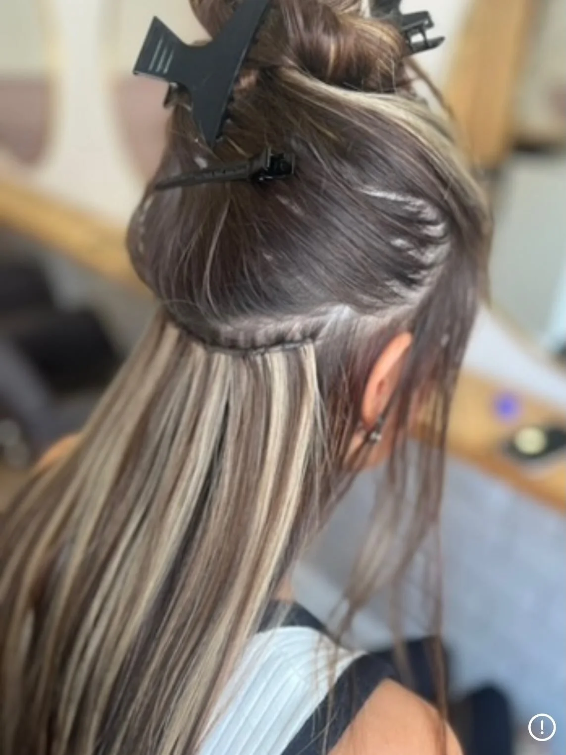 A woman getting her hair highlighted with foils at a hair salon.