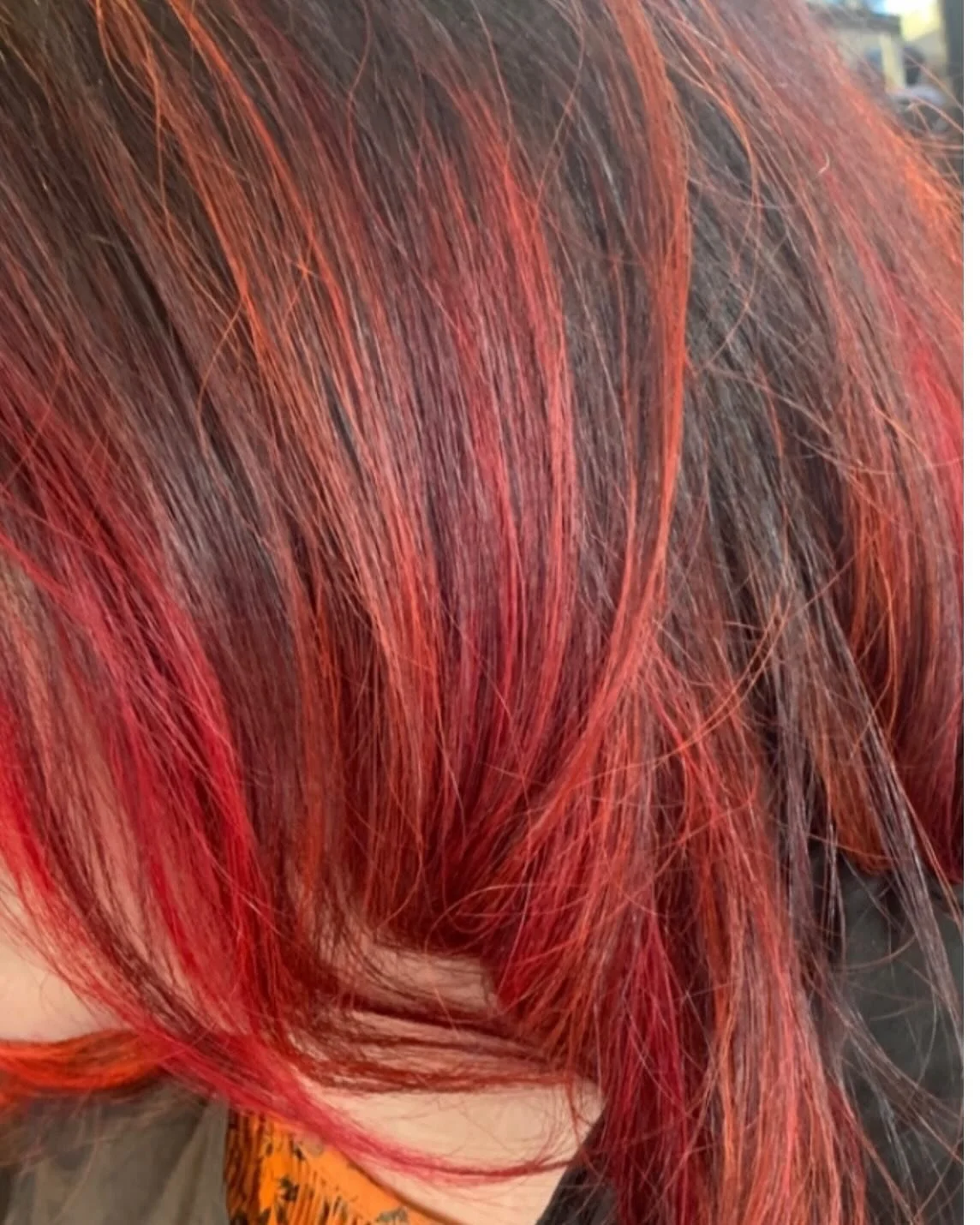 Close-up of vibrant red hair with shades of orange and dark undertones.