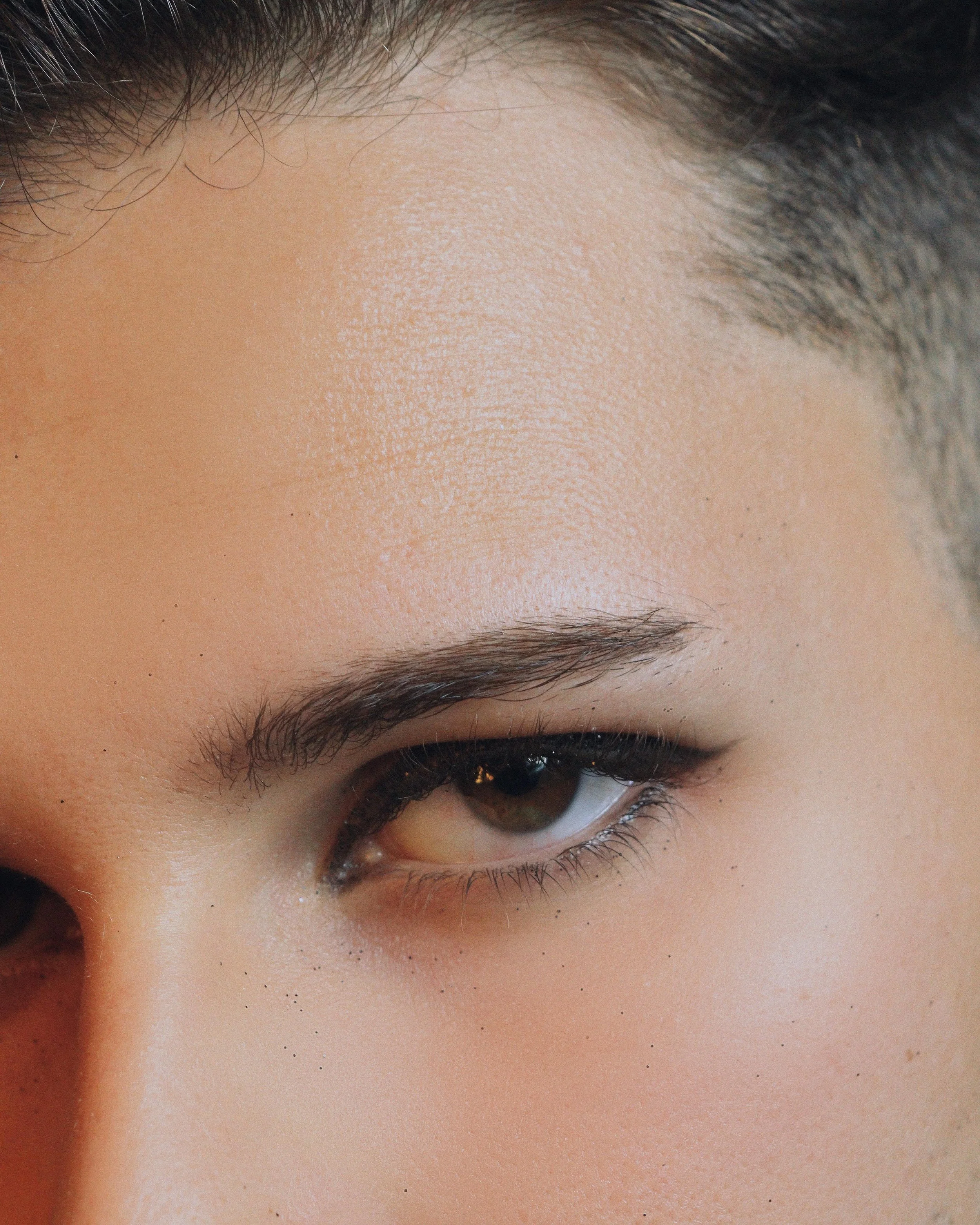 Close-up of a person's eye, eyebrow, and forehead with clear skin and dark hair. Lisa B Hair & Beauty Salon, Carlisle, Cumbria UK.