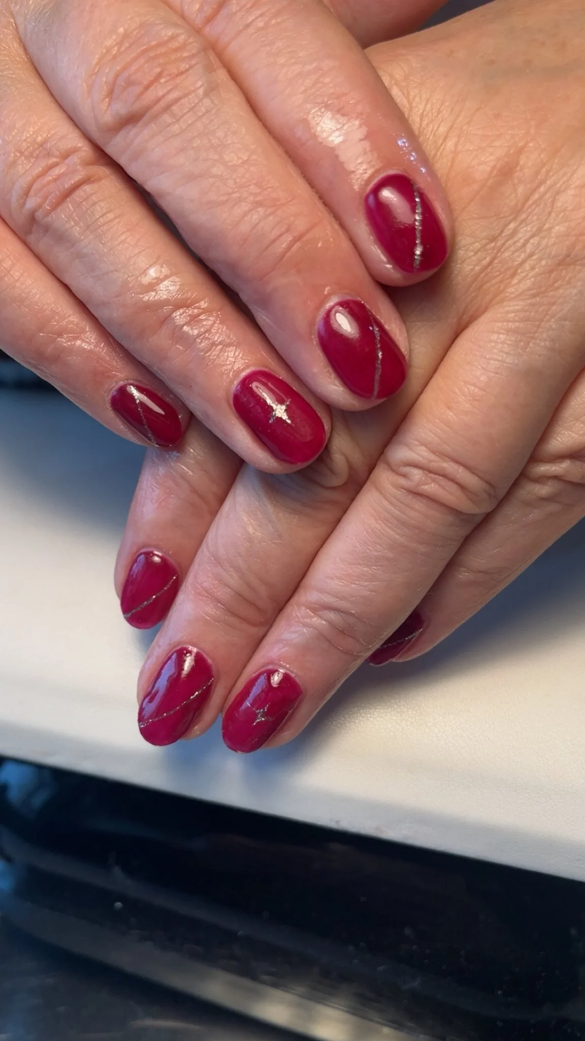 Close-up of hands with red painted nails featuring a silver stripe design. Award winning Lisa B Hair and Beauty Salon in Carlisle, Cumbria UK.