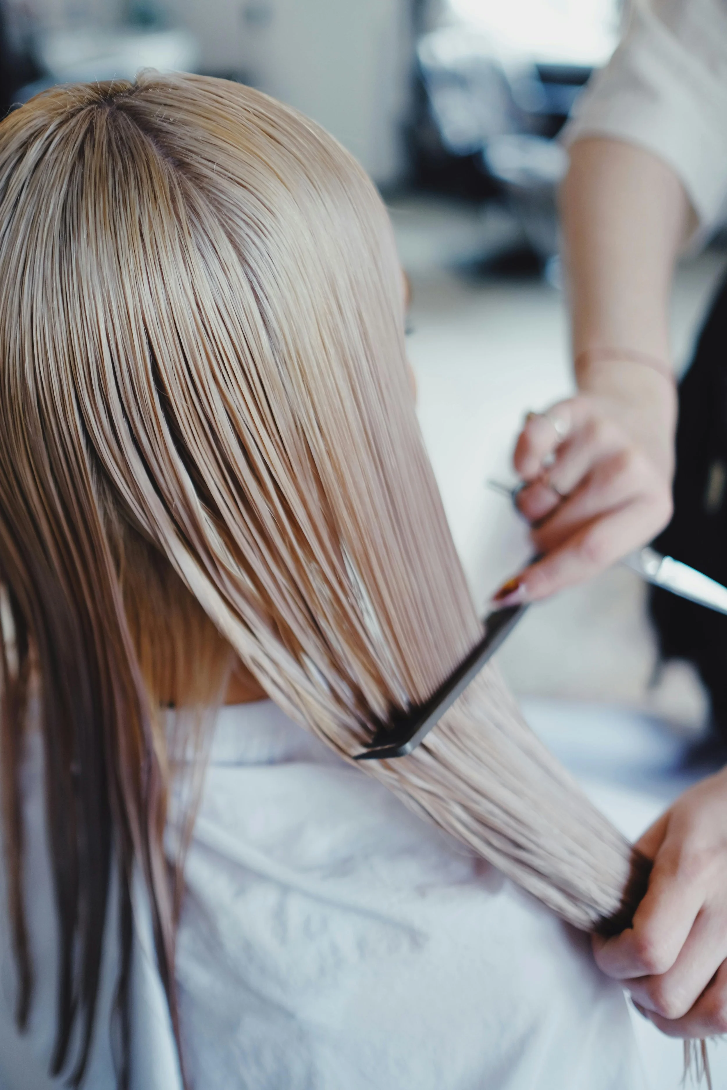 A woman with long blonde hair is sitting at a salon, getting her hair styled or dyed by a stylist. Lisa B Hair & Beauty Salon, Carlisle, Cumbria UK.