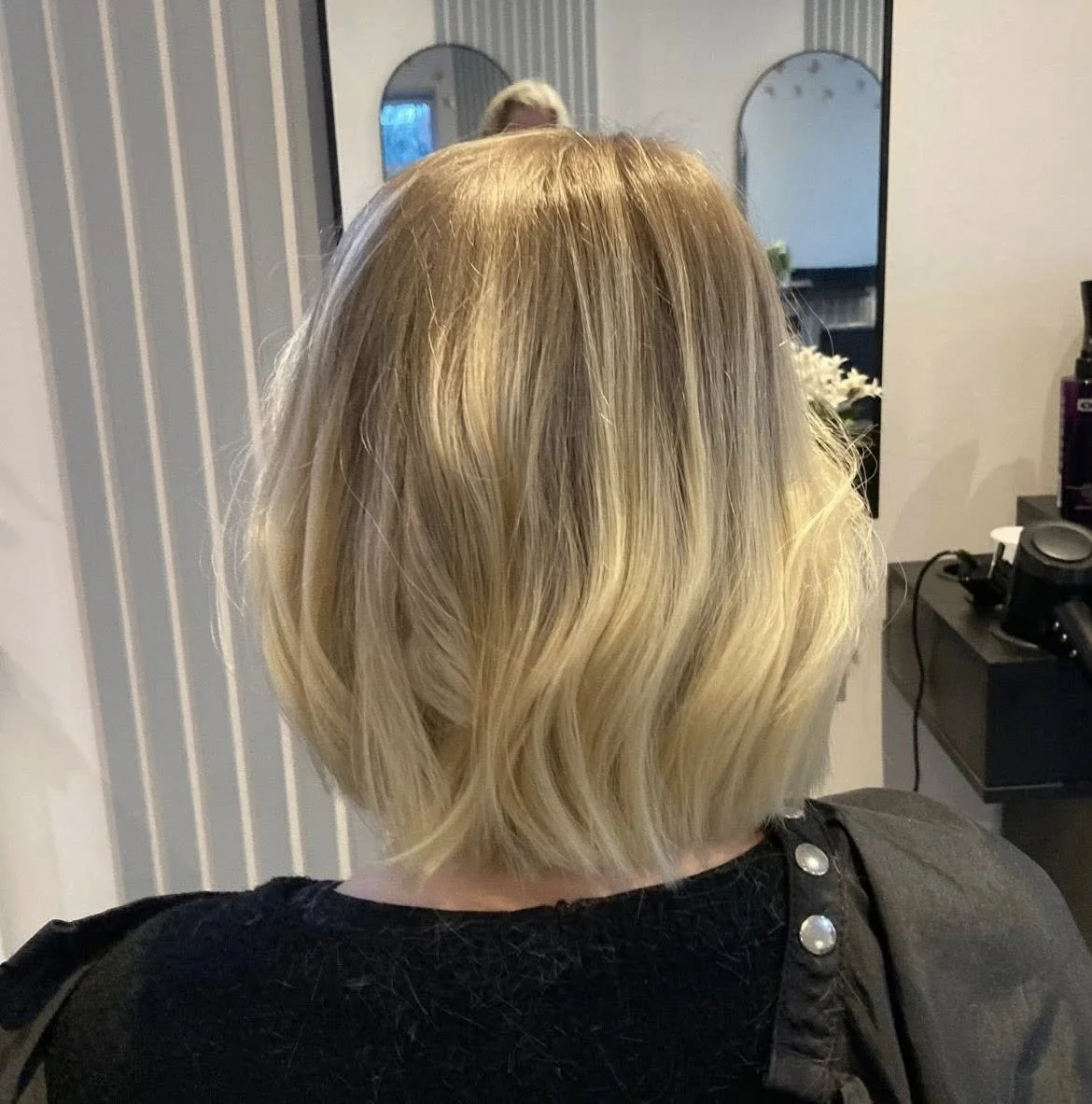 Back of a woman with a blonde bob haircut, sitting in a salon chair in front of a mirror. Lisa B Hair & Beauty Salon, Carlisle, Cumbria UK.