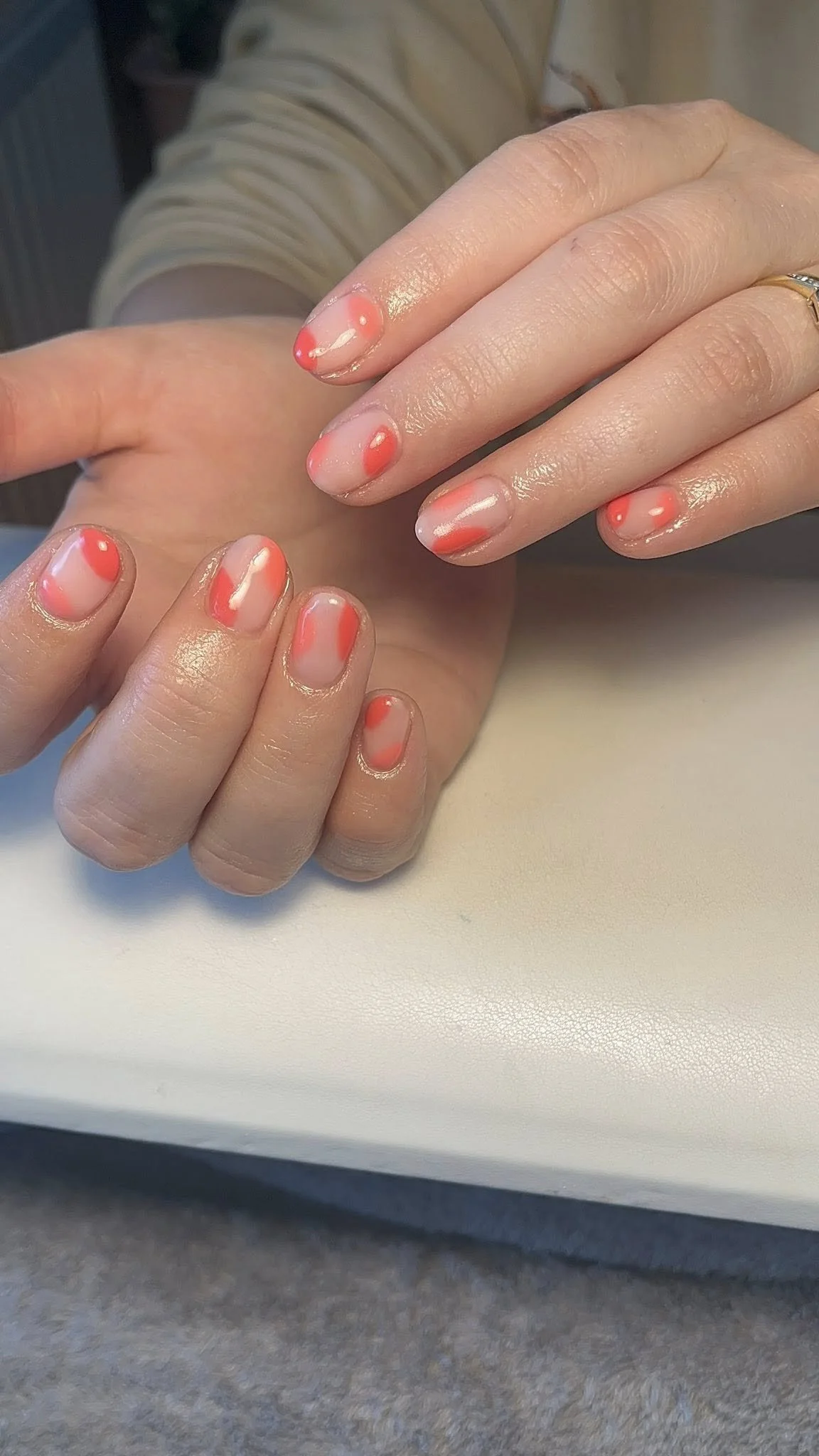Close-up of a person's hand with freshly painted nails featuring a design with a white base and bright orange accents.