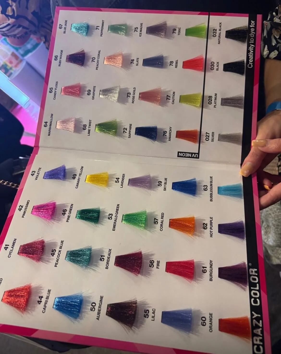 Color sample chart with various hair dye shades arranged in rows and columns, including colors like violet, yellow, green, blue, red, purple, orange, and black, each with a number and name label.