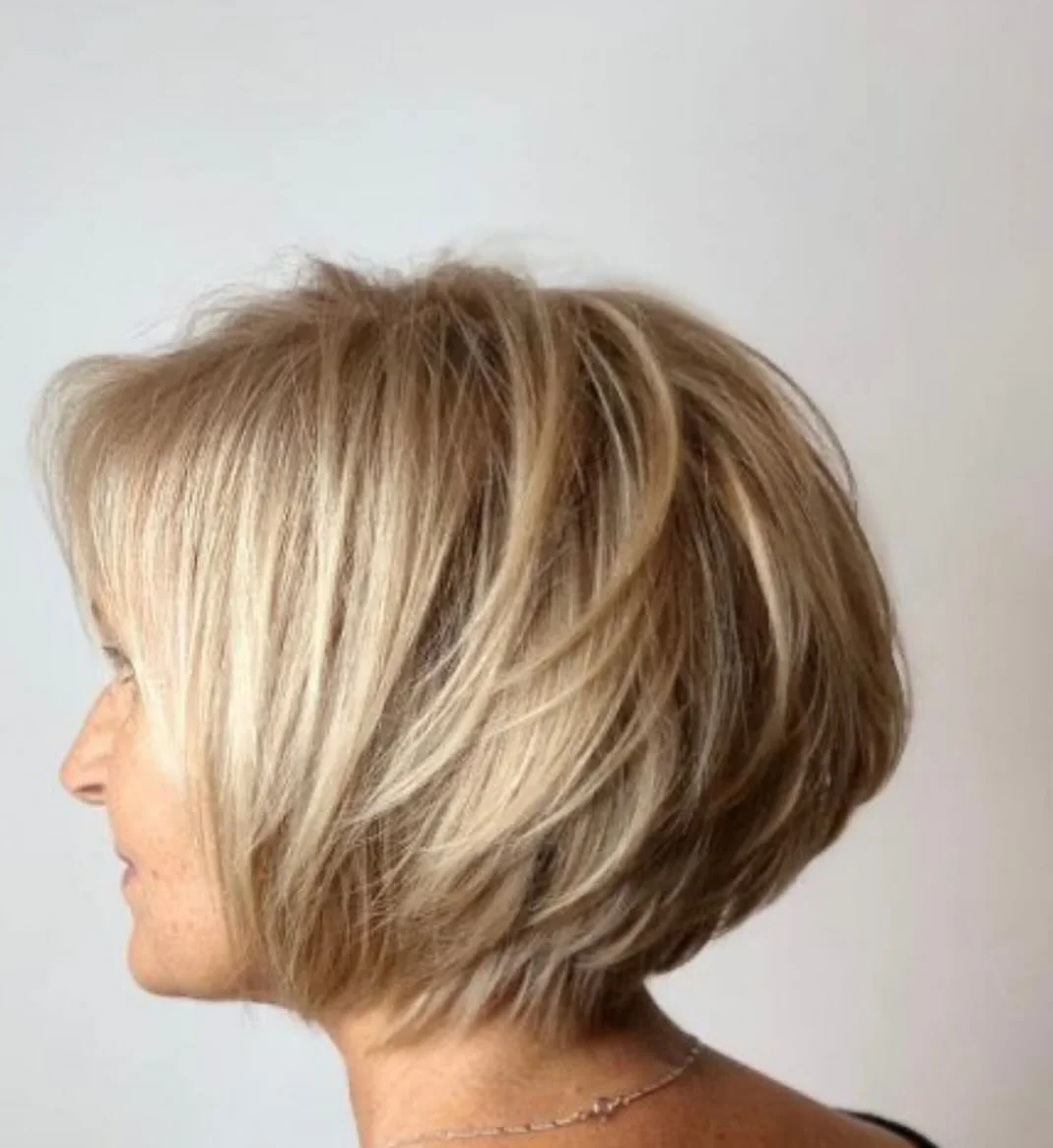 Side view of a woman with a short layered blonde bob haircut.