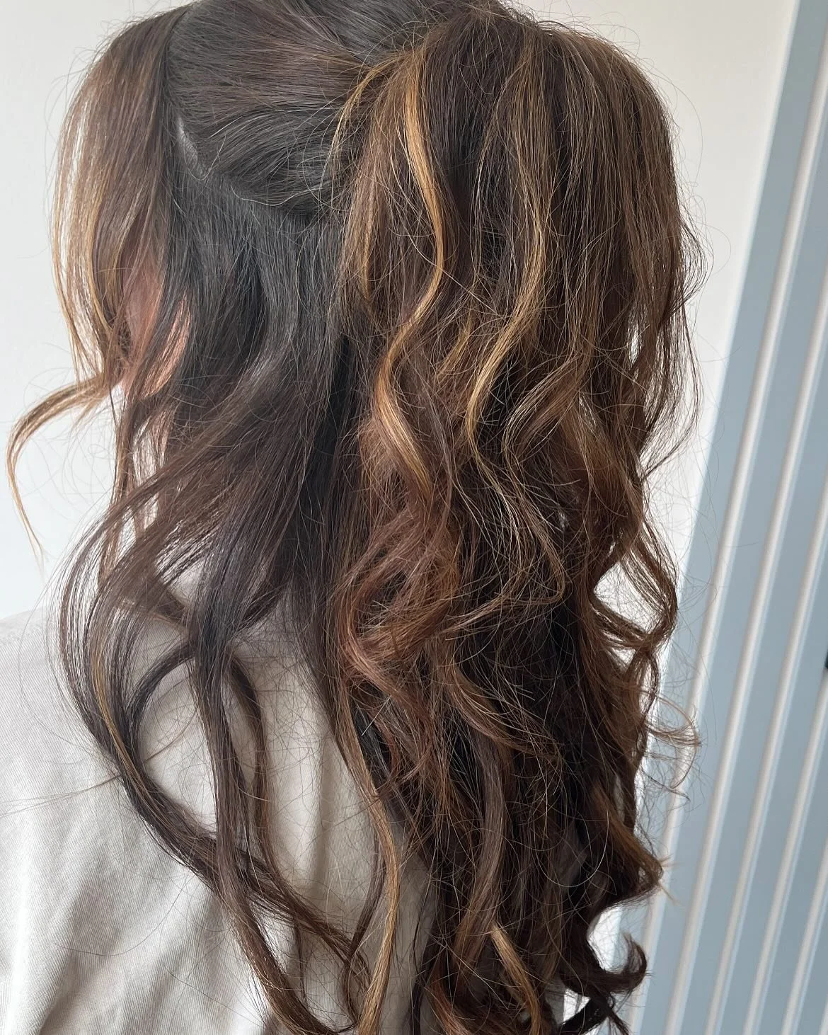Close-up of a woman's wavy, layered hair with caramel and dark brown highlights at Lisa B Hair & Beauty Salon, Carlisle, Cumbria UK.
