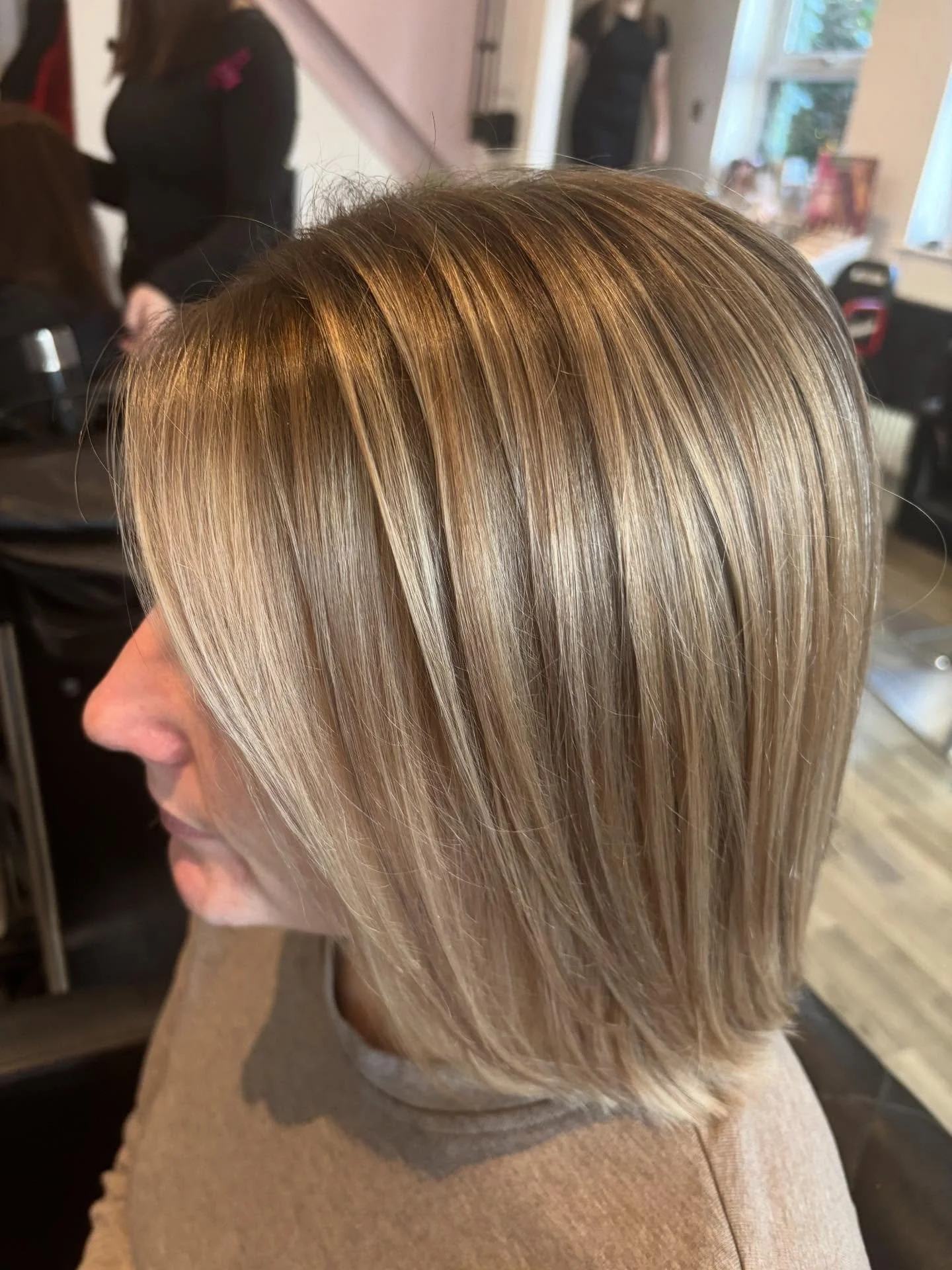 Close-up of a woman's blonde hair styled in a sleek, layered bob, with a salon background. Lisa B Hair & Beauty Salon, Carlisle, Cumbria UK.
