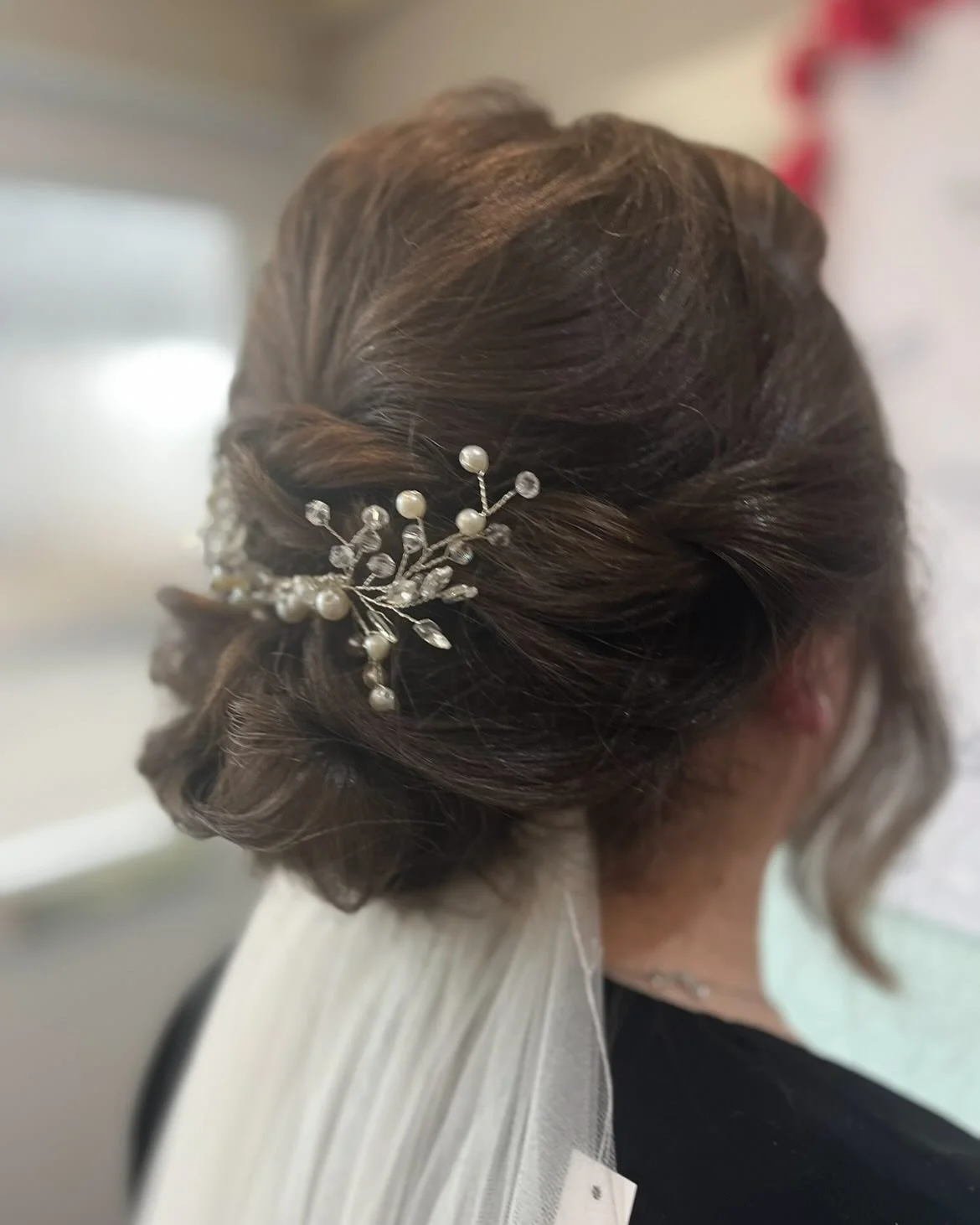Close-up of a woman's styled brown hair updo with a pearl and rhinestone decorative hair pin. Lisa B Hair & Beauty Salon, Carlisle, Cumbria UK.