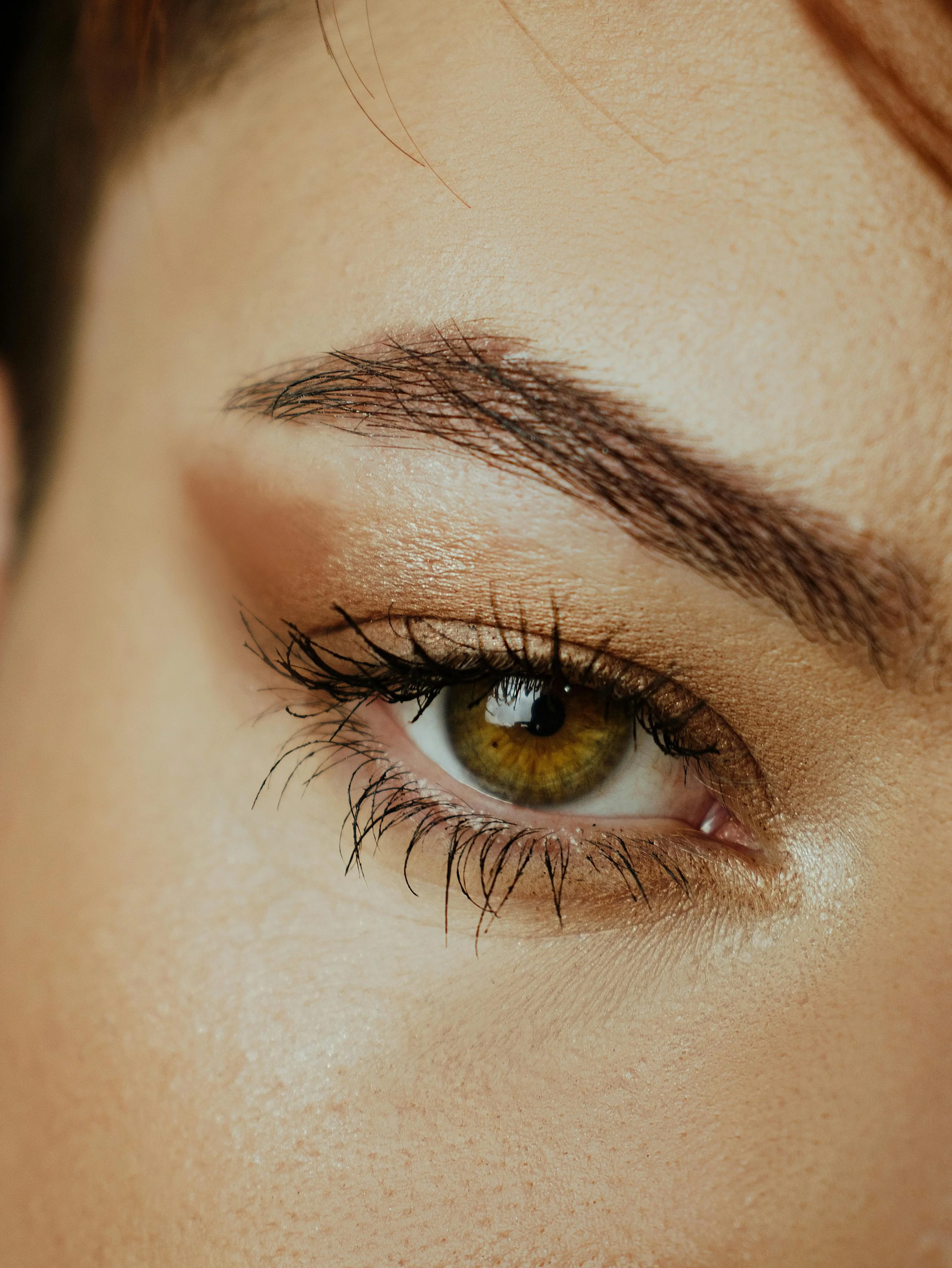 Close-up of a person's closed eye with long, dark eyelashes and well-groomed eyebrow, with eye makeup. Lisa B Hair & Beauty Salon, Carlisle, Cumbria UK.