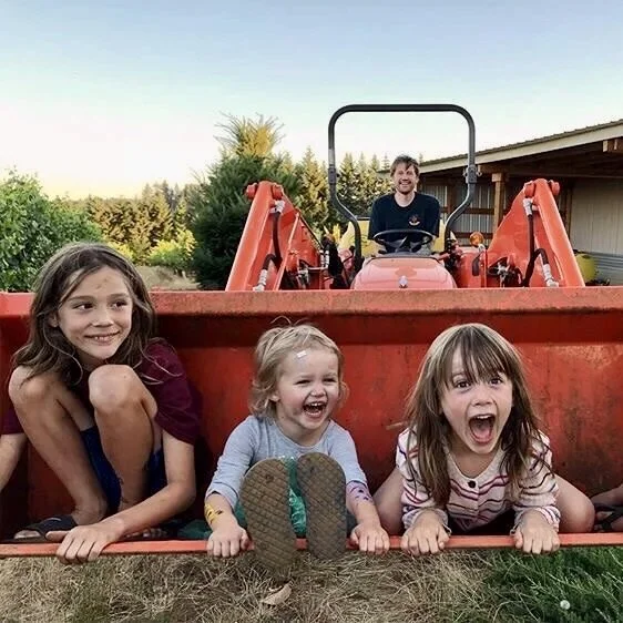 Our kids sit in the bucket of the tractor at the Breaker Vineyard in Eola-Amity Hills AVA .