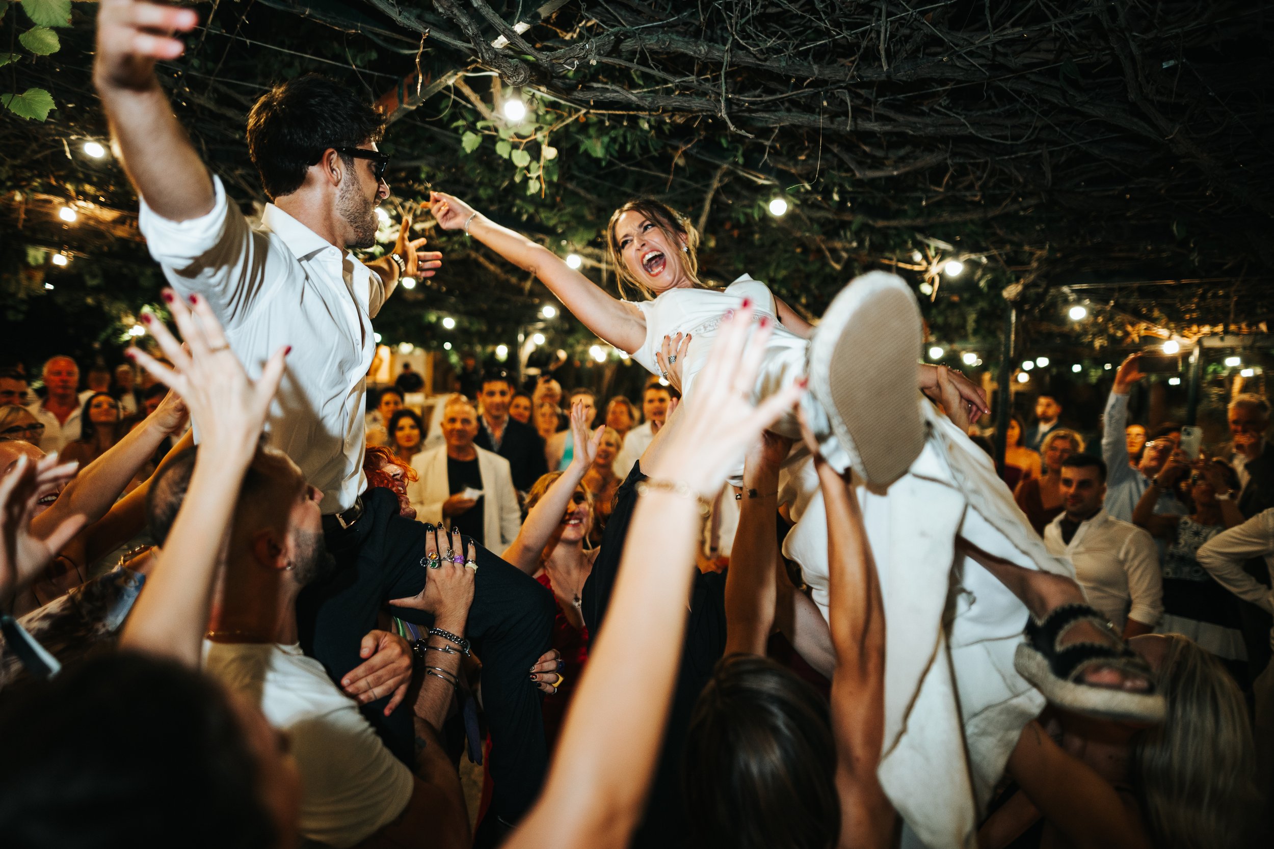 A woman crowd surfing at an indoor event with people reaching out to support her.