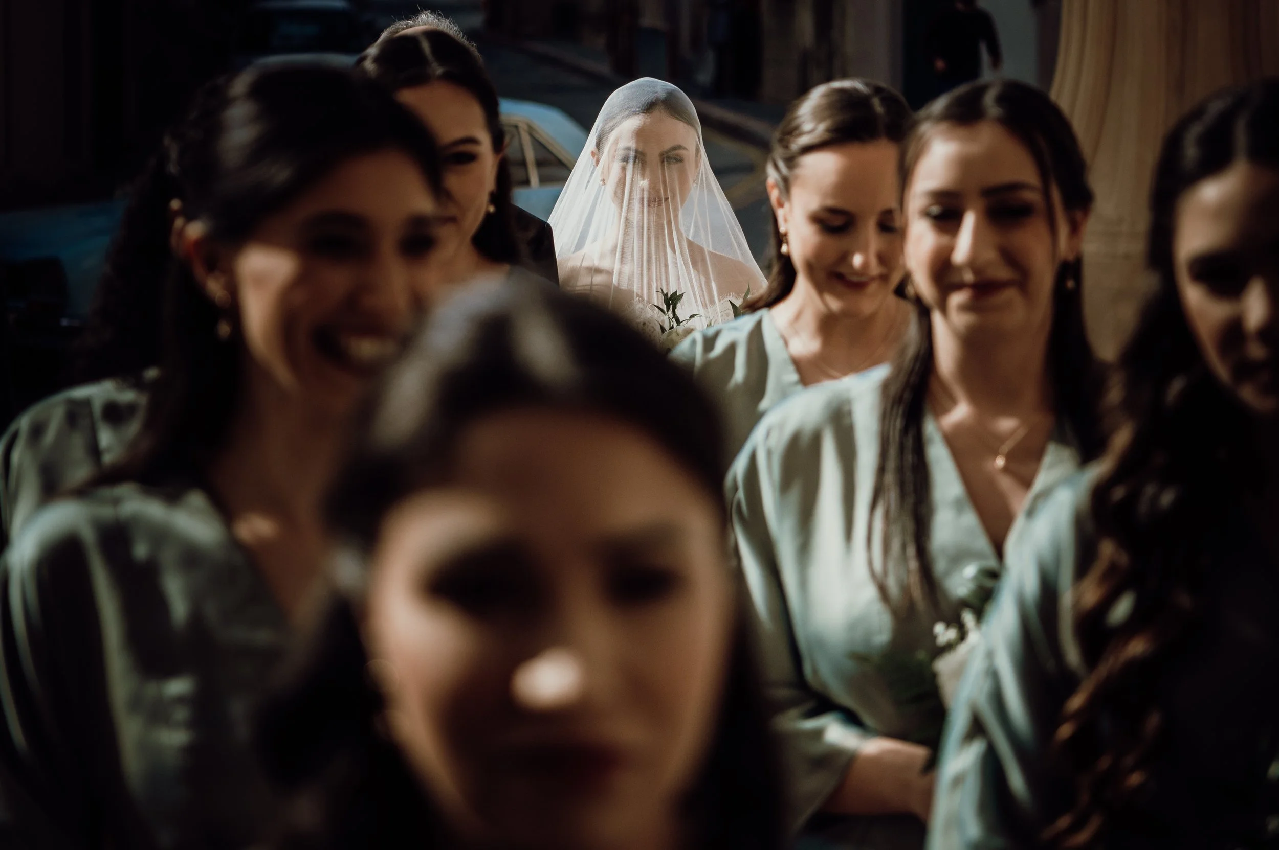 A bride with a veil and a group of women, likely bridesmaids, standing nearby.