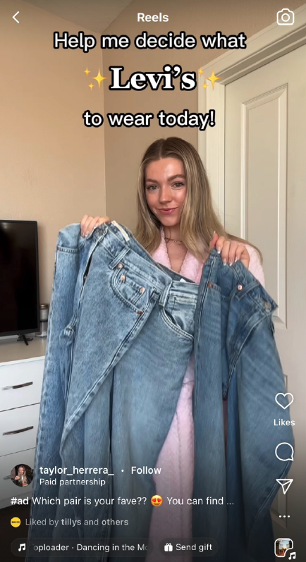 Young woman holding up two pairs of denim Levi's jeans, one in each hand, in a bedroom. Text overlay reads, "Help me decide what Levi's to wear today!"