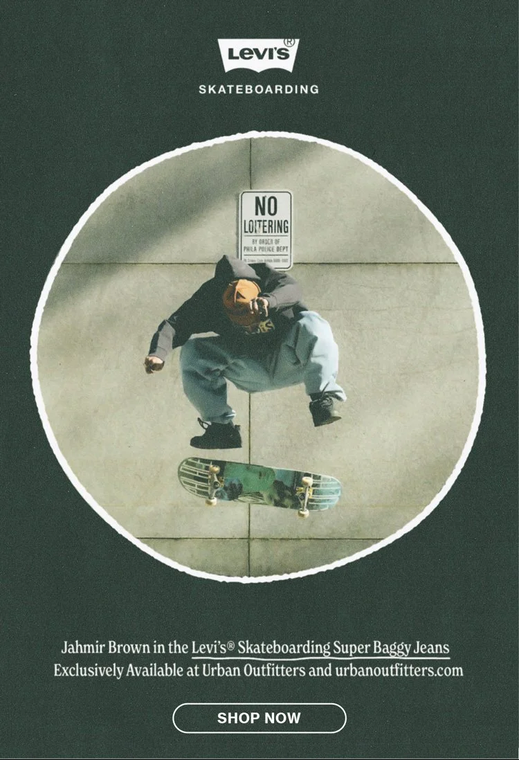 A person skateboarding on a city sidewalk, viewed from above. The skateboarder is wearing a black hoodie and blue jeans. There is a sign that reads 'No Loitering' on the wall behind, and Levi's branding is visible at the top. The image promotes Levi's skateboard super baggy jeans available at Urban Outfitters.