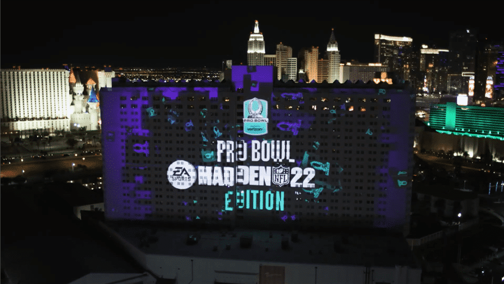 Night view of a large building in Las Vegas with illuminated signs and the text "Pro Bowl Madden NFL 22 Edition" projected onto it, with the Las Vegas skyline in the background.