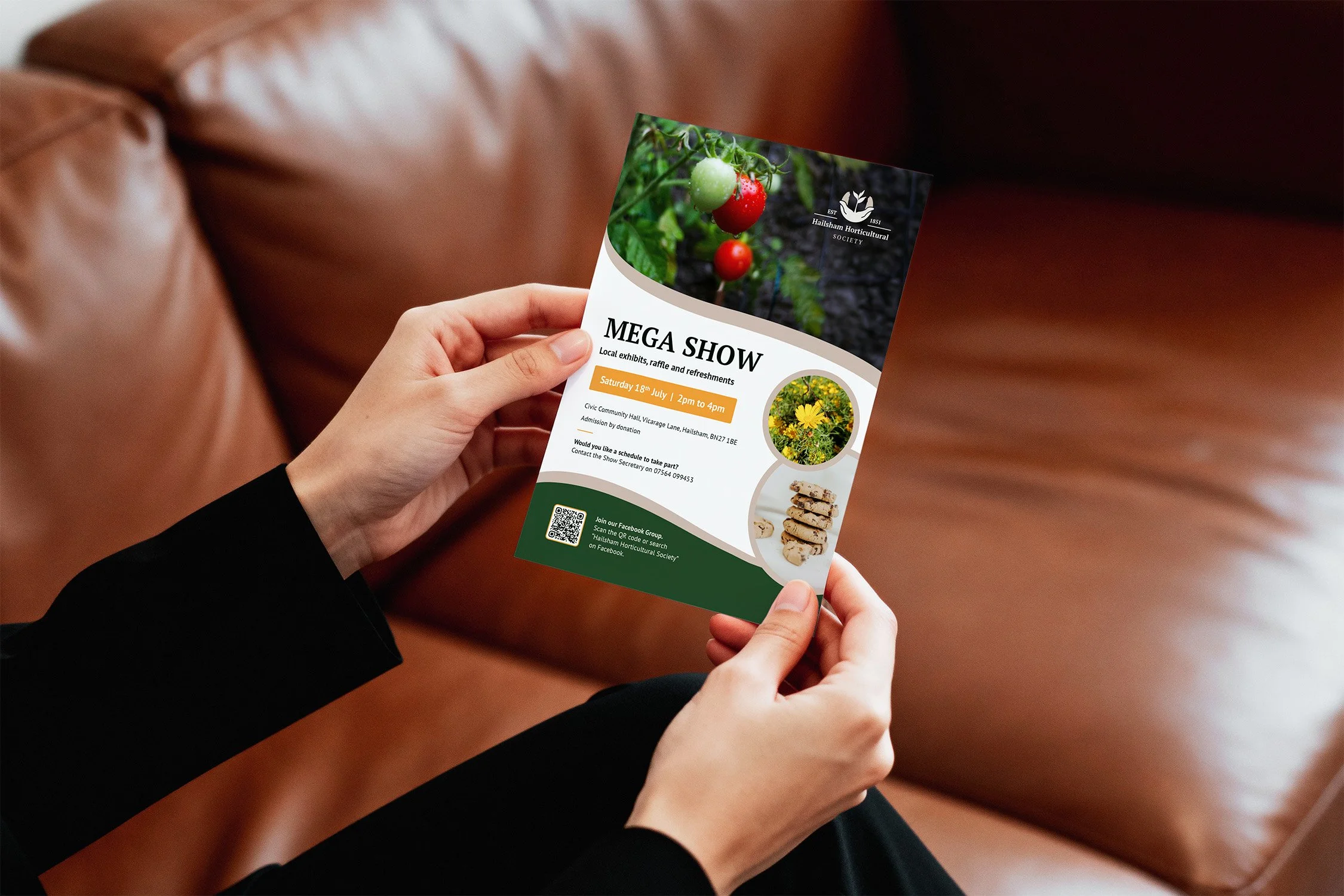 Person holding a flyer for the Hailsham Horticultural Society's Mega Show with images of tomatoes, flowers, and cookies.