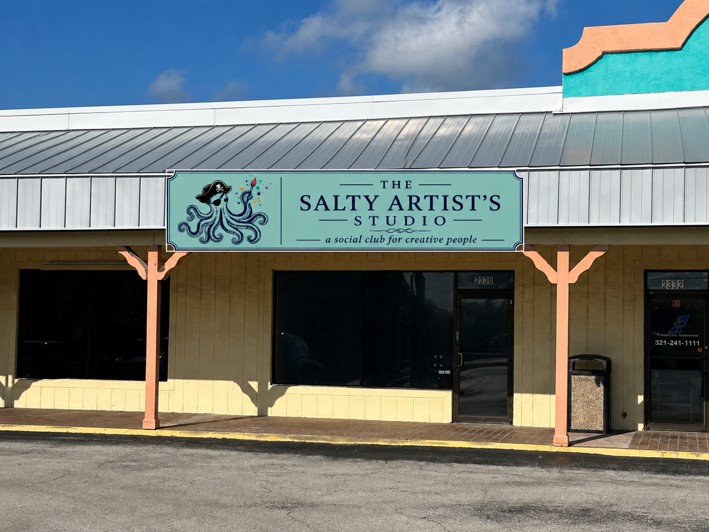 Exterior of a building with a sign reading 'The Salty Artist's Studio, a social club for creative people,' featuring a cartoon octopus wearing a pirate hat and holding a paintbrush.