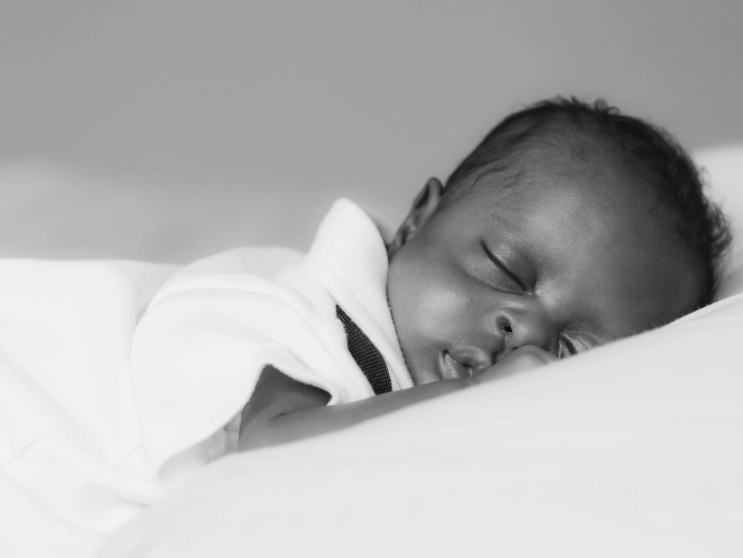 Schlafendes Baby mit geschlossenen Augen, das auf einem weißen Kissen liegt.