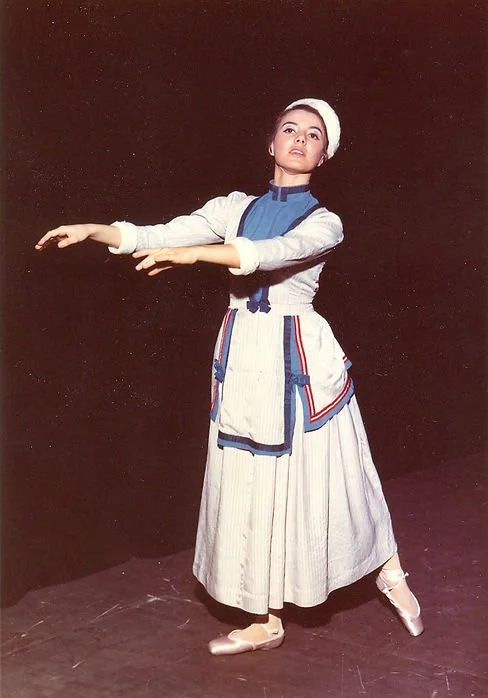 Una ballerina in costume tradizionale che esegue una coreografia sul palco.