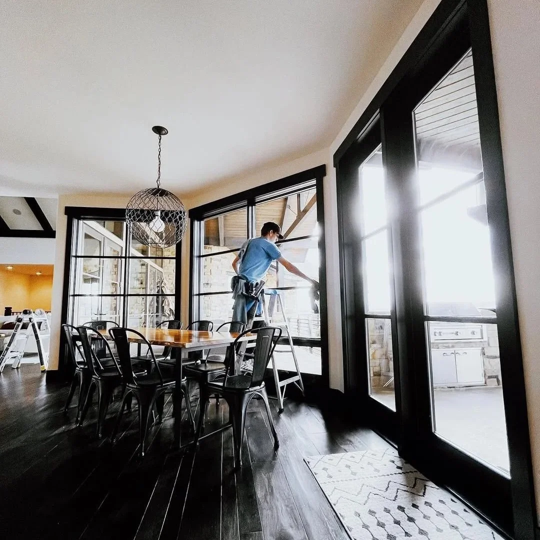 Rise & Shine technician cleaning the inside of a large dining room window in a Northern Colorado home