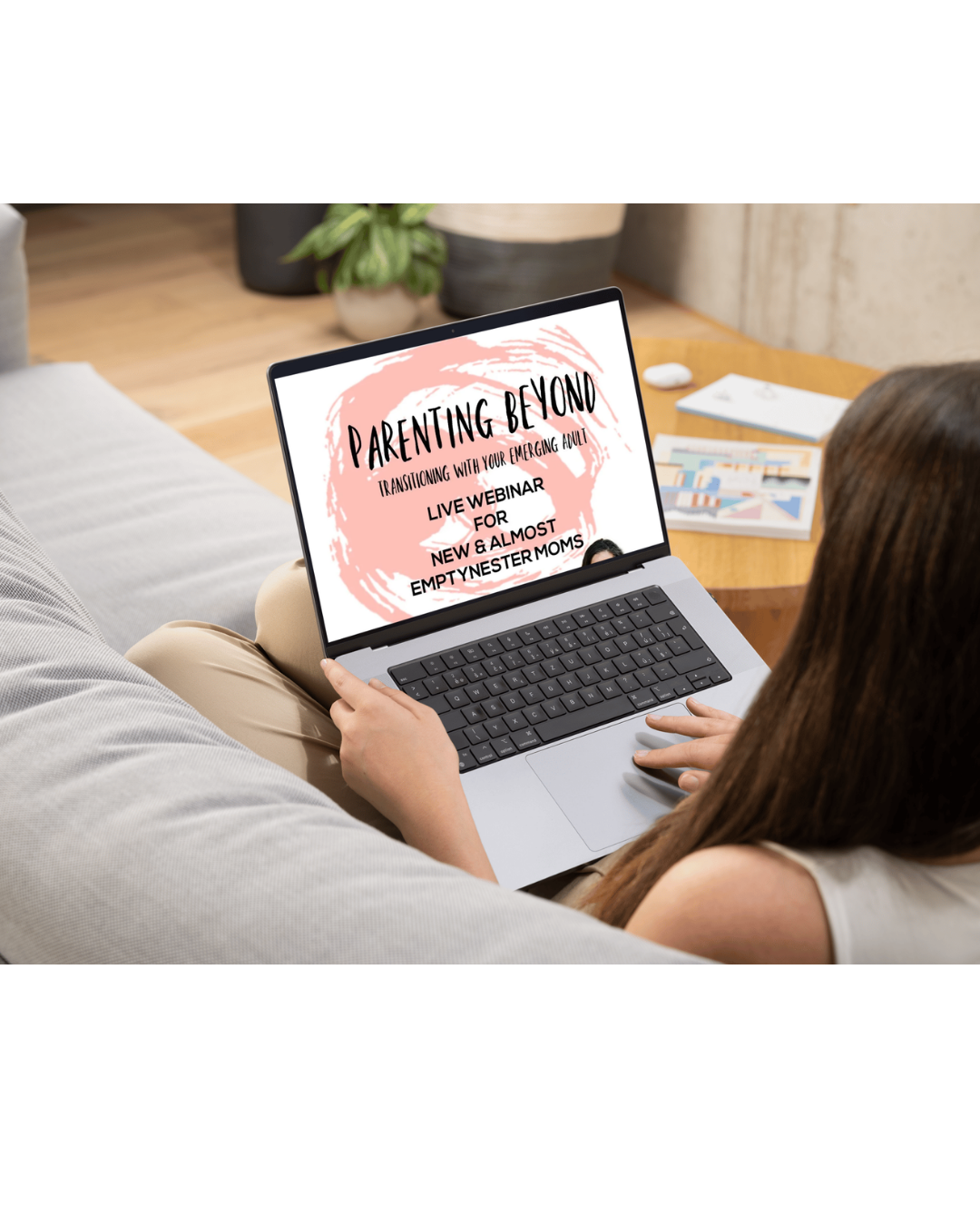Person sitting on a couch using a laptop that displays a webinar titled 'Parenting Beyond: Transitioning with Your Emerging Adult'.