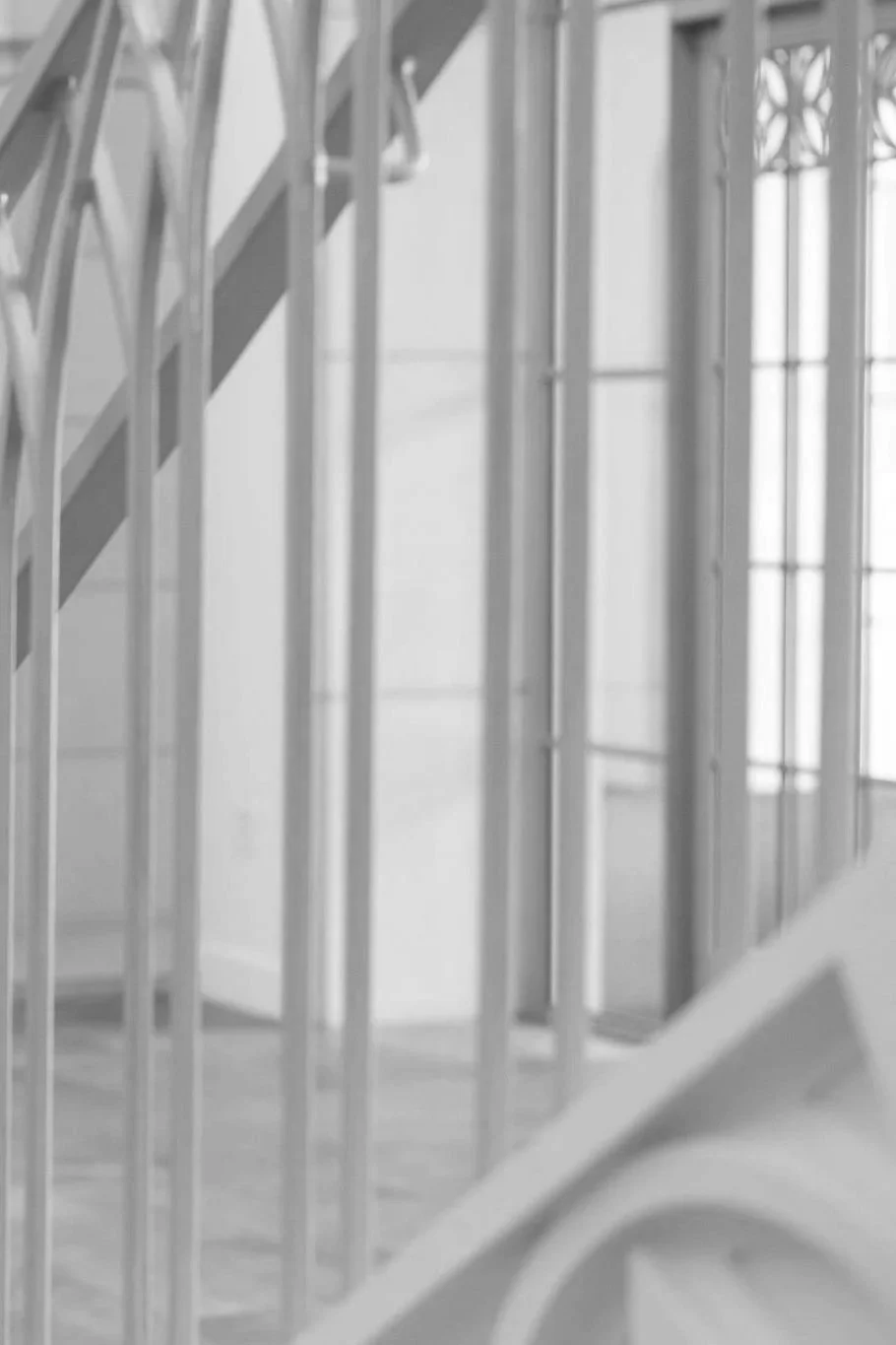 Close-up of a staircase railing with vertical metal bars and a partial view of stairs.