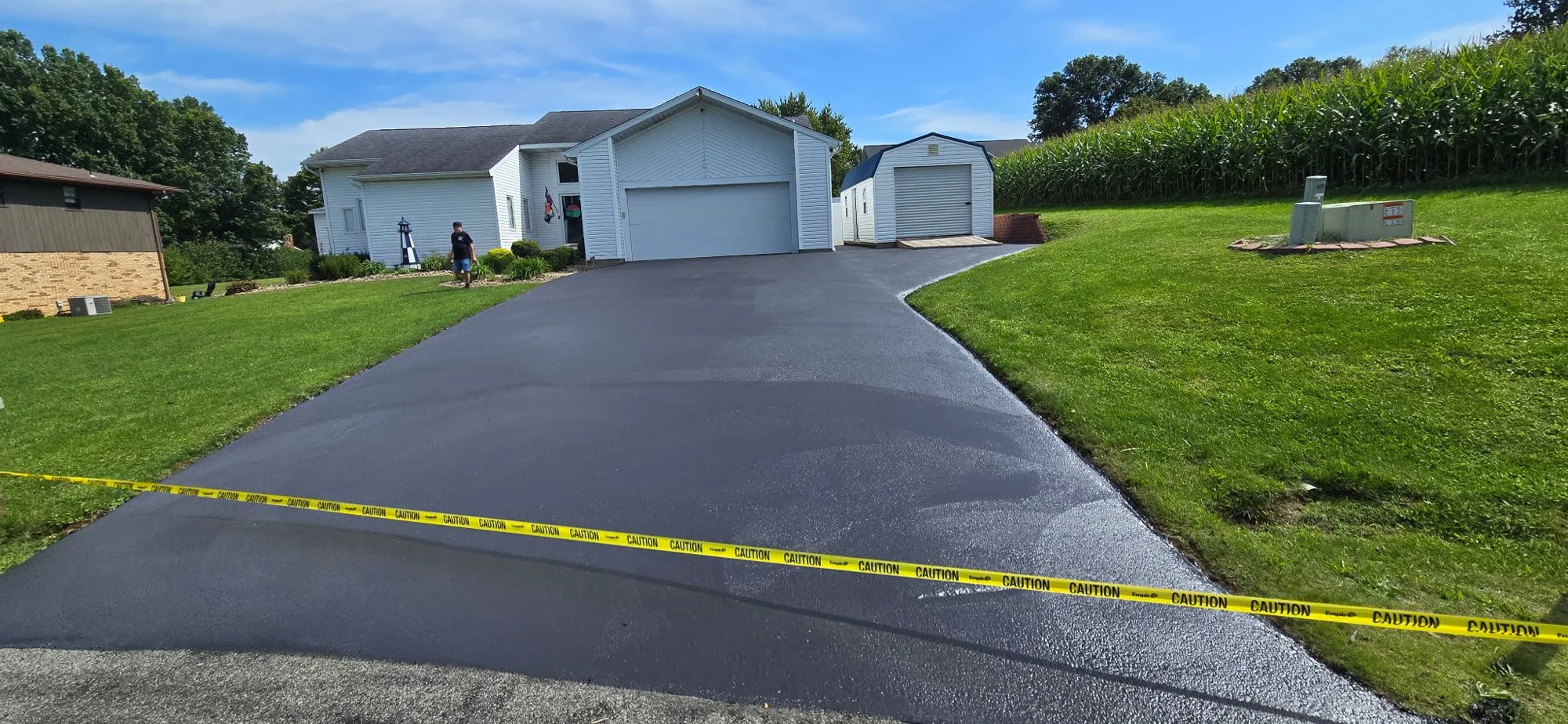Freshly sealed asphalt driveway with caution tape in Butler, PA