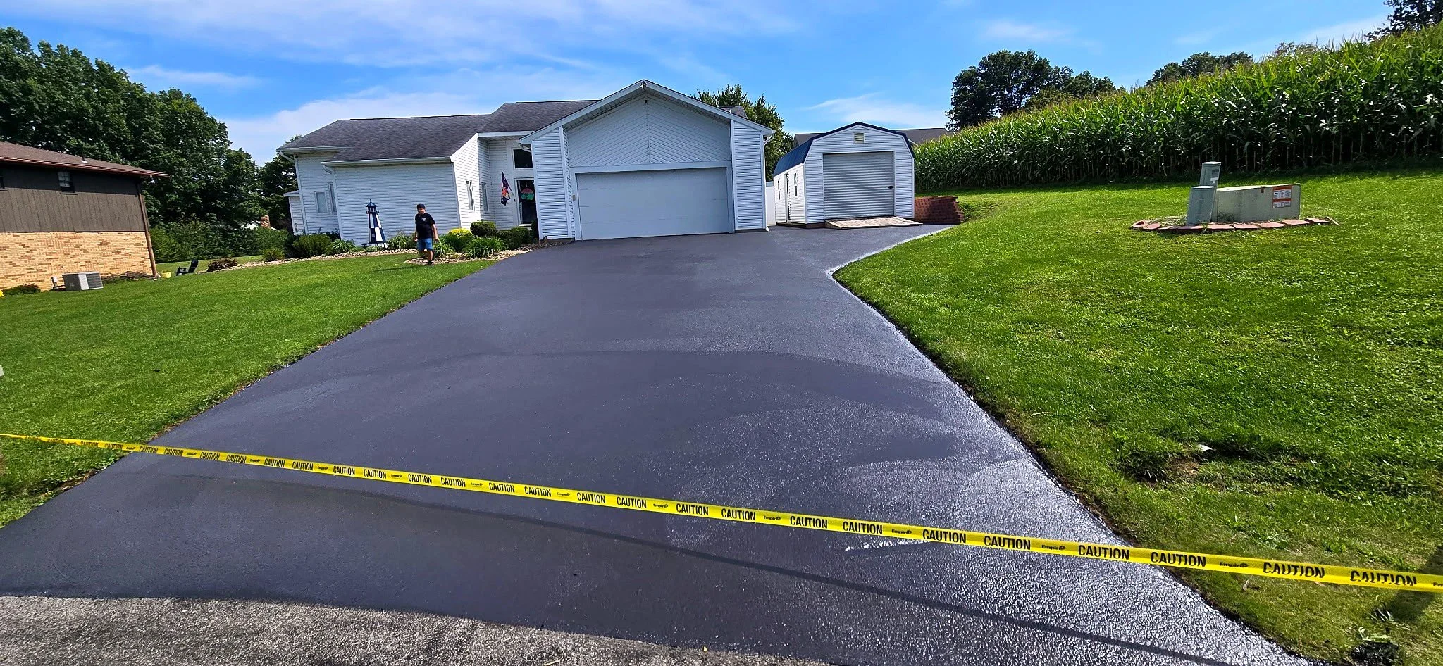 Newly sealed asphalt driveway with caution tape in Butler, PA