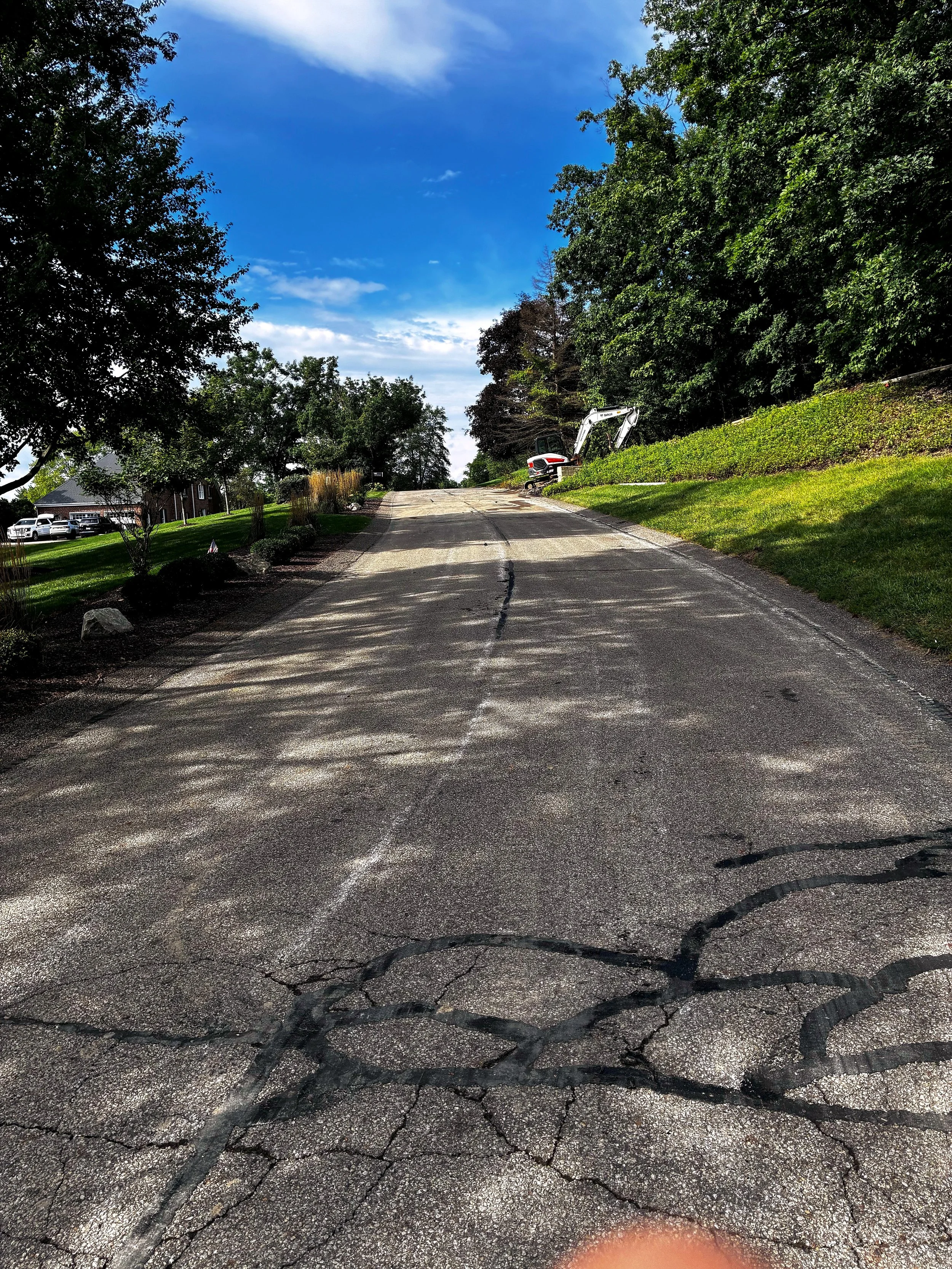 Cracked asphalt driveway running uphill in Butler, PA