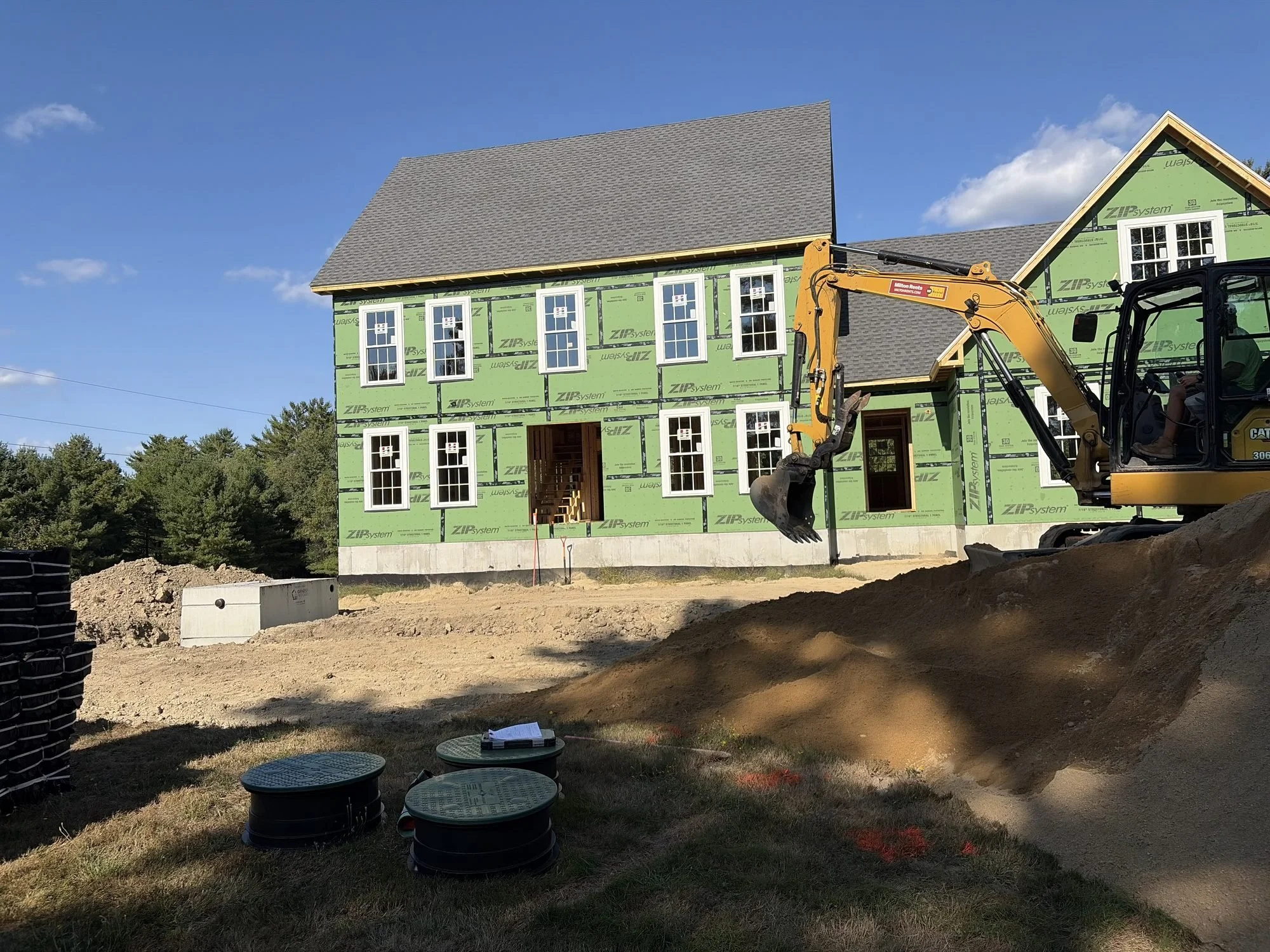 Septic tank installation with access risers and excavator on site in Cumberland County, Maine
