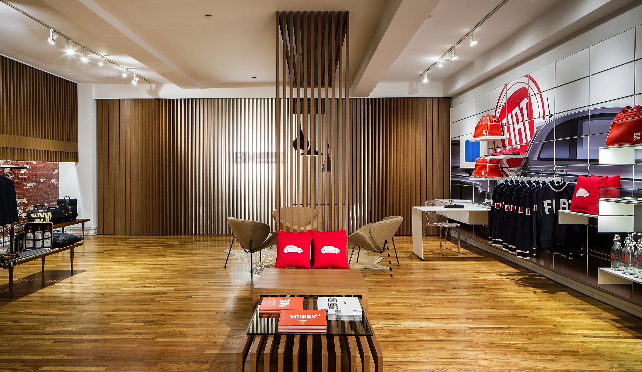 Interior of a modern retail store showcasing Fiat merchandise, including backpacks, apparel, and accessories, with wooden accents and warm lighting.