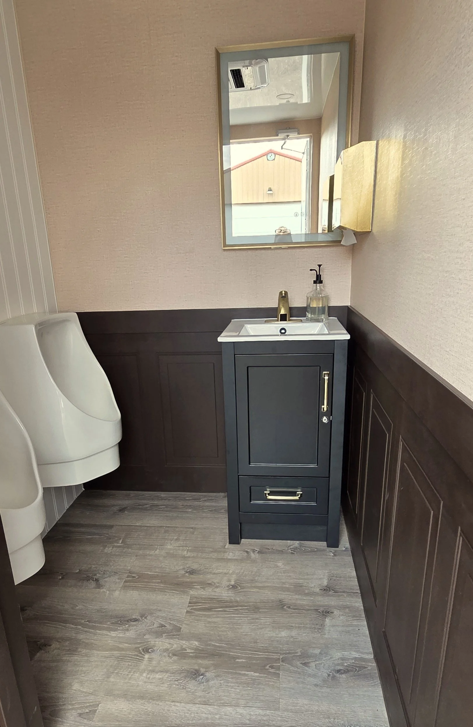 A FIESTA LUXURY bathroom with a black vanity, a white sink, a mirror, a soap dispenser, a faucet, a mirror,  and a bidet to the left