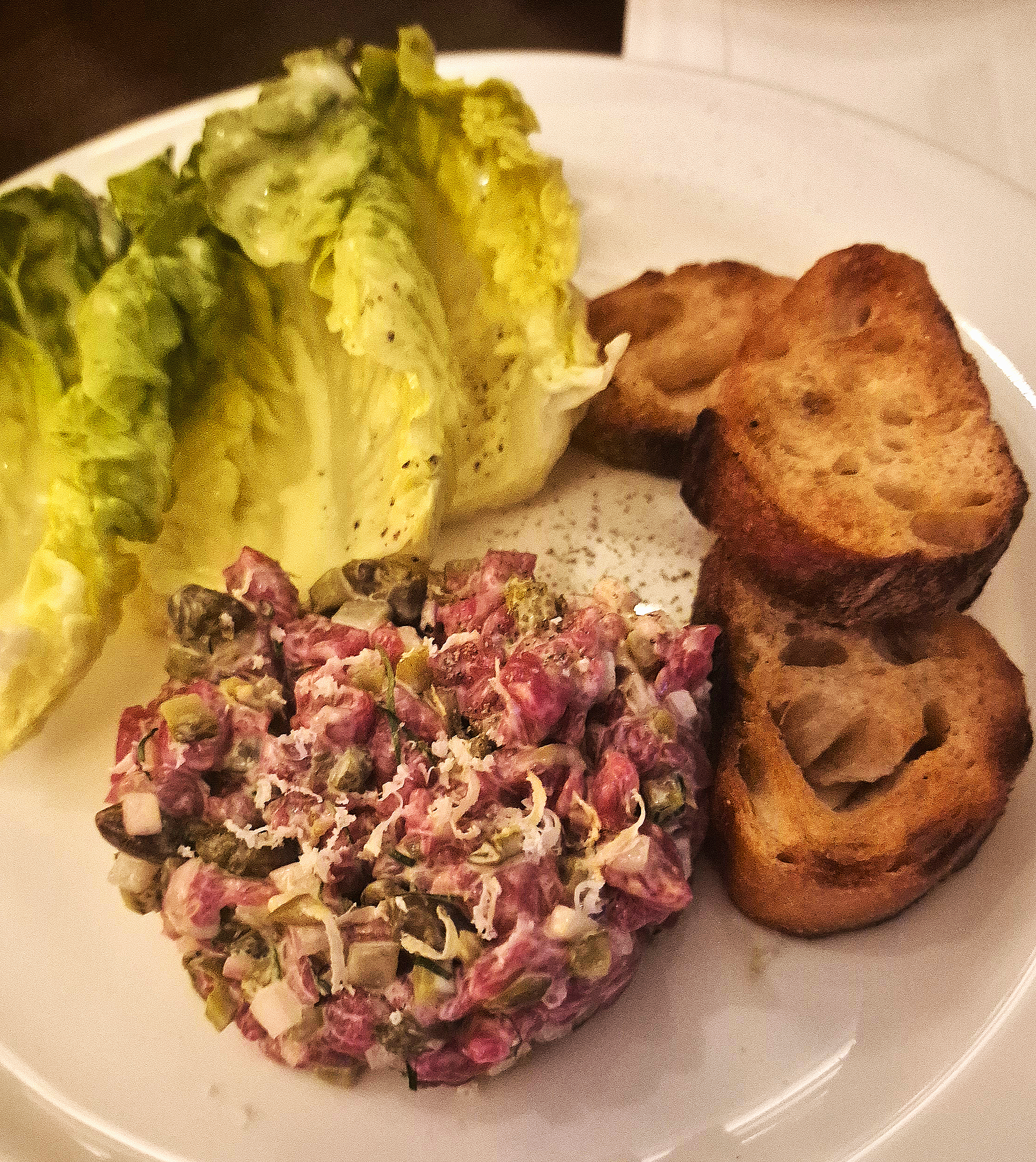 Steak tartare with grilled baguette and lettuce.