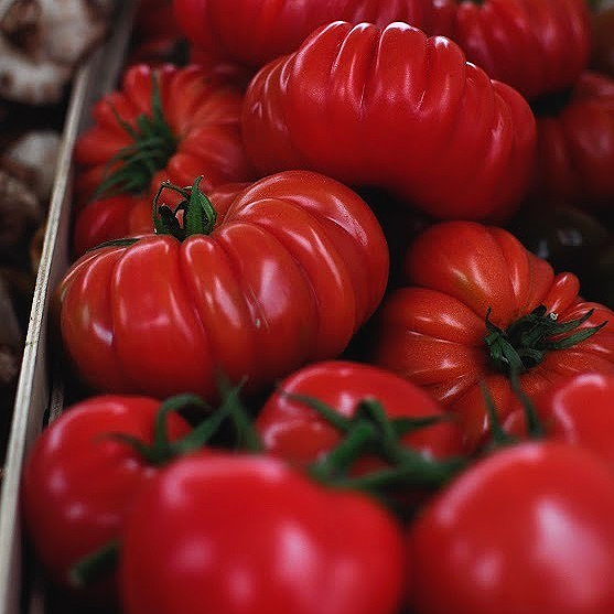 Close-up of ripe red heirloom tomatoes on a display.
