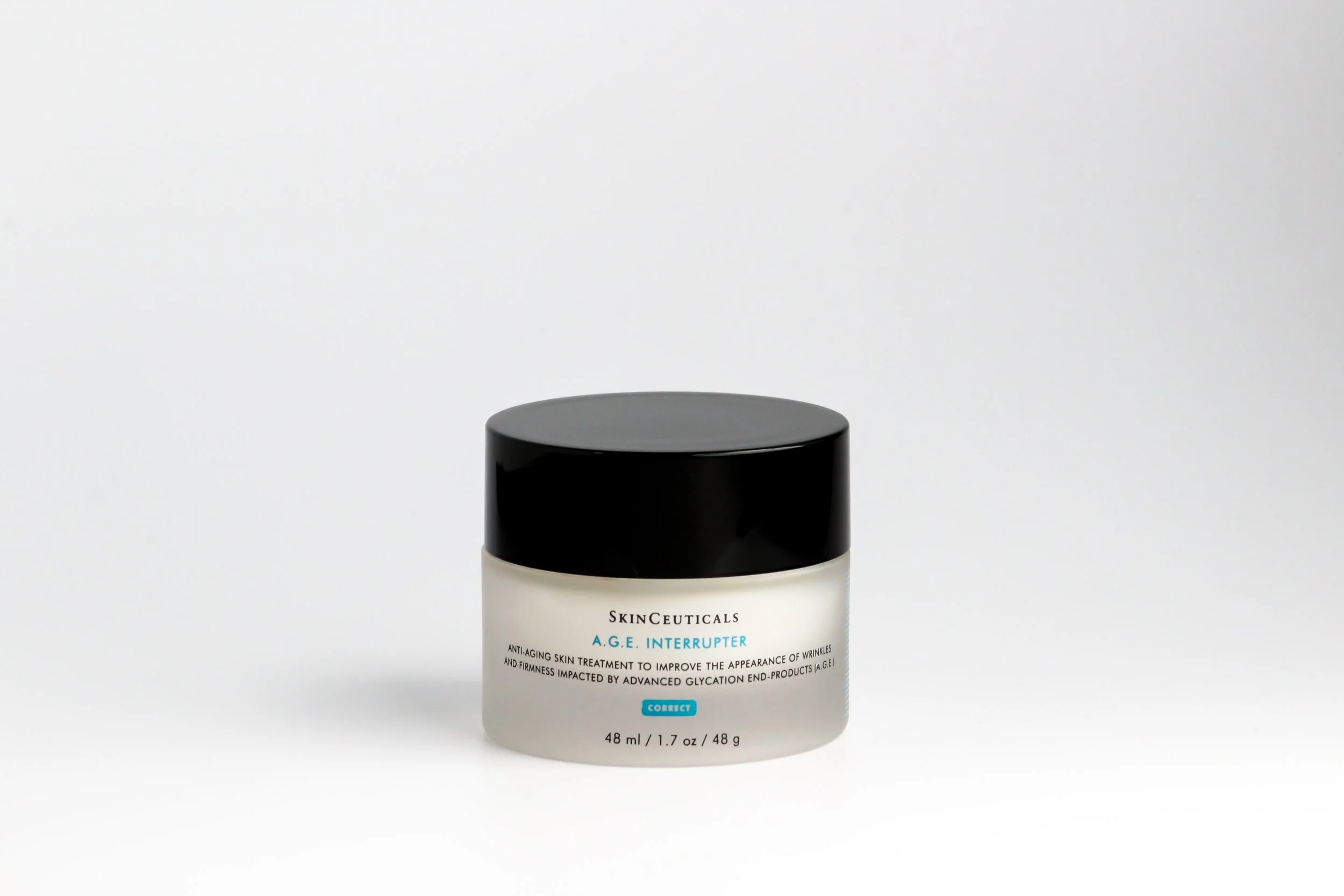 A jar of SkinCeuticals A.G.E. Interrupter anti-aging skin treatment with a black cap and white body, displayed against a plain white background.