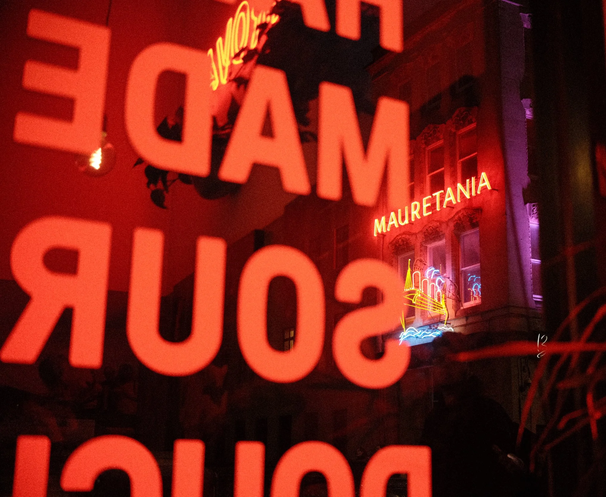 Neon sign on building wall reading 'EL GAT' in red and orange colors.