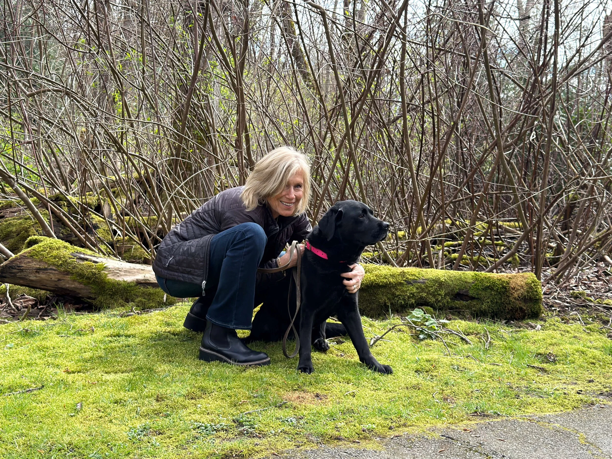 Seattle life coach Paula Freeman of Affirmative Coaching smiles while crouching next to her dog Chloe.