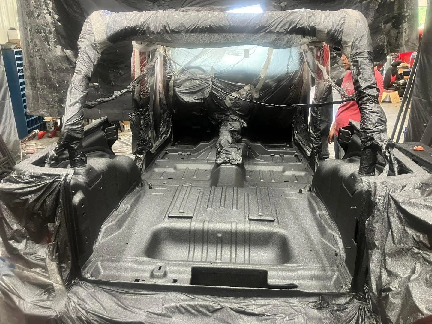Technician applying a spray-on bedliner to a truck in Columbus, IN