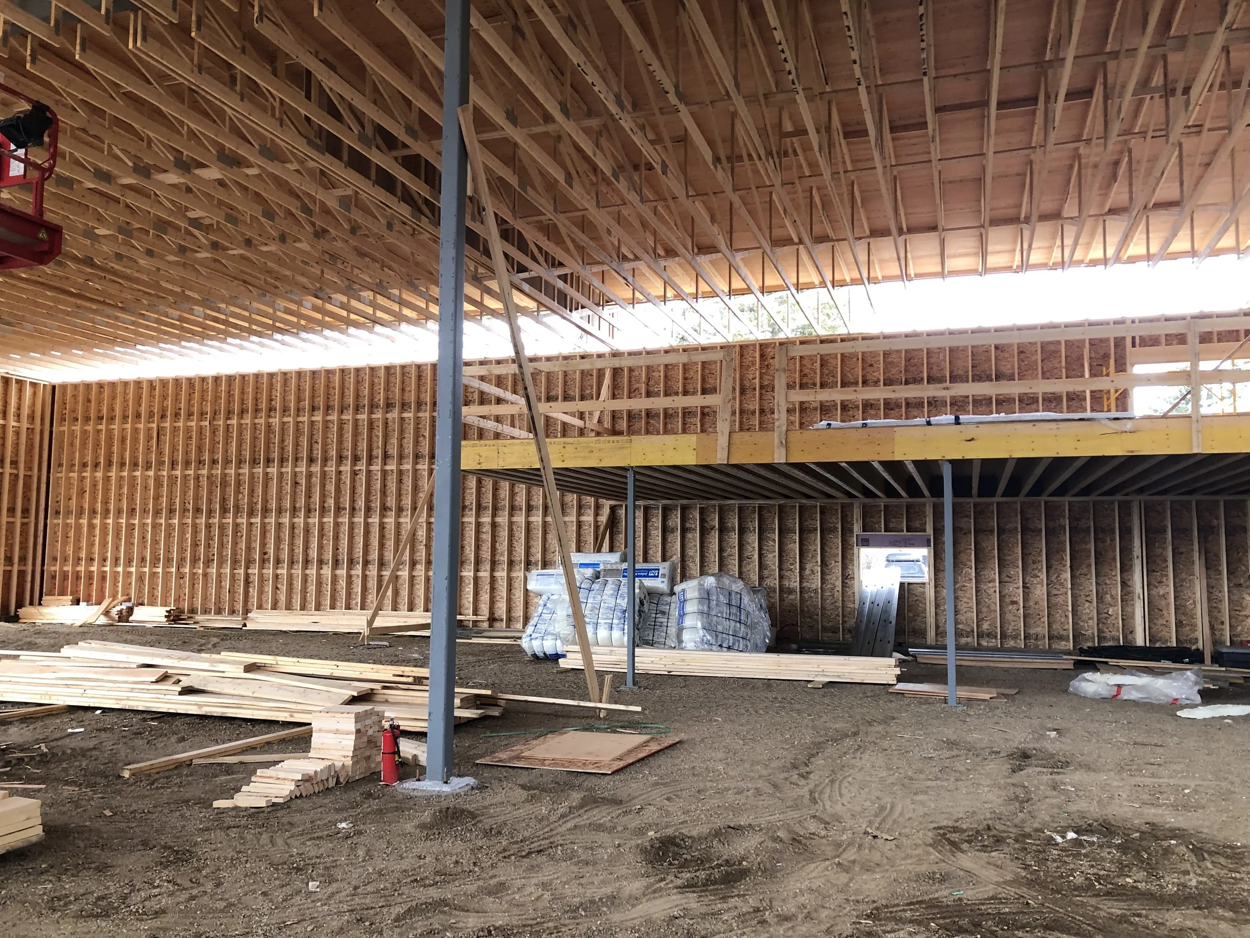 Construction site with wooden framing for a building, scattered wood planks on the ground, and construction materials.