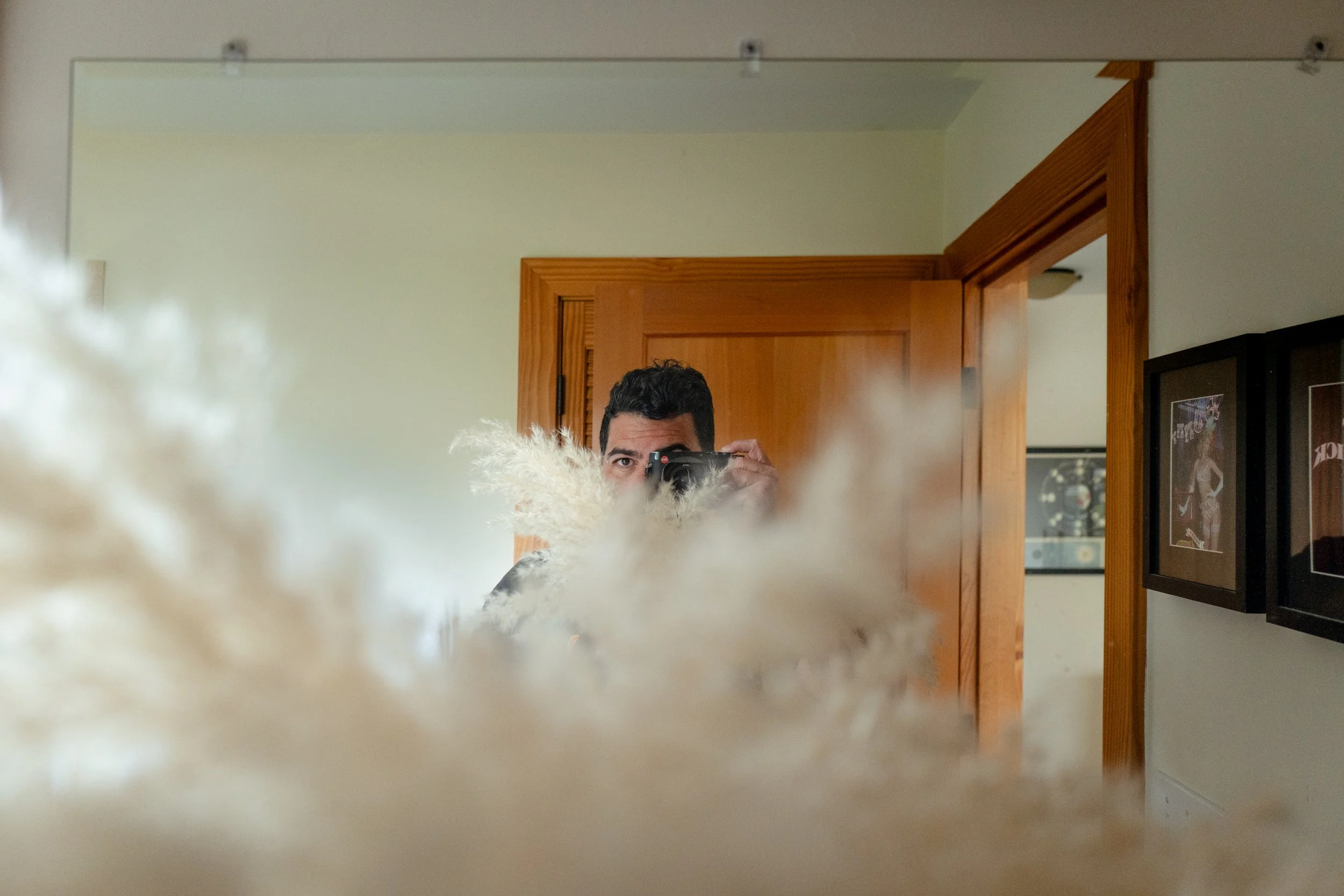 Self-portrait of Seattle photographer Ricardo Gotla holding his camera, framed by soft pampas grass