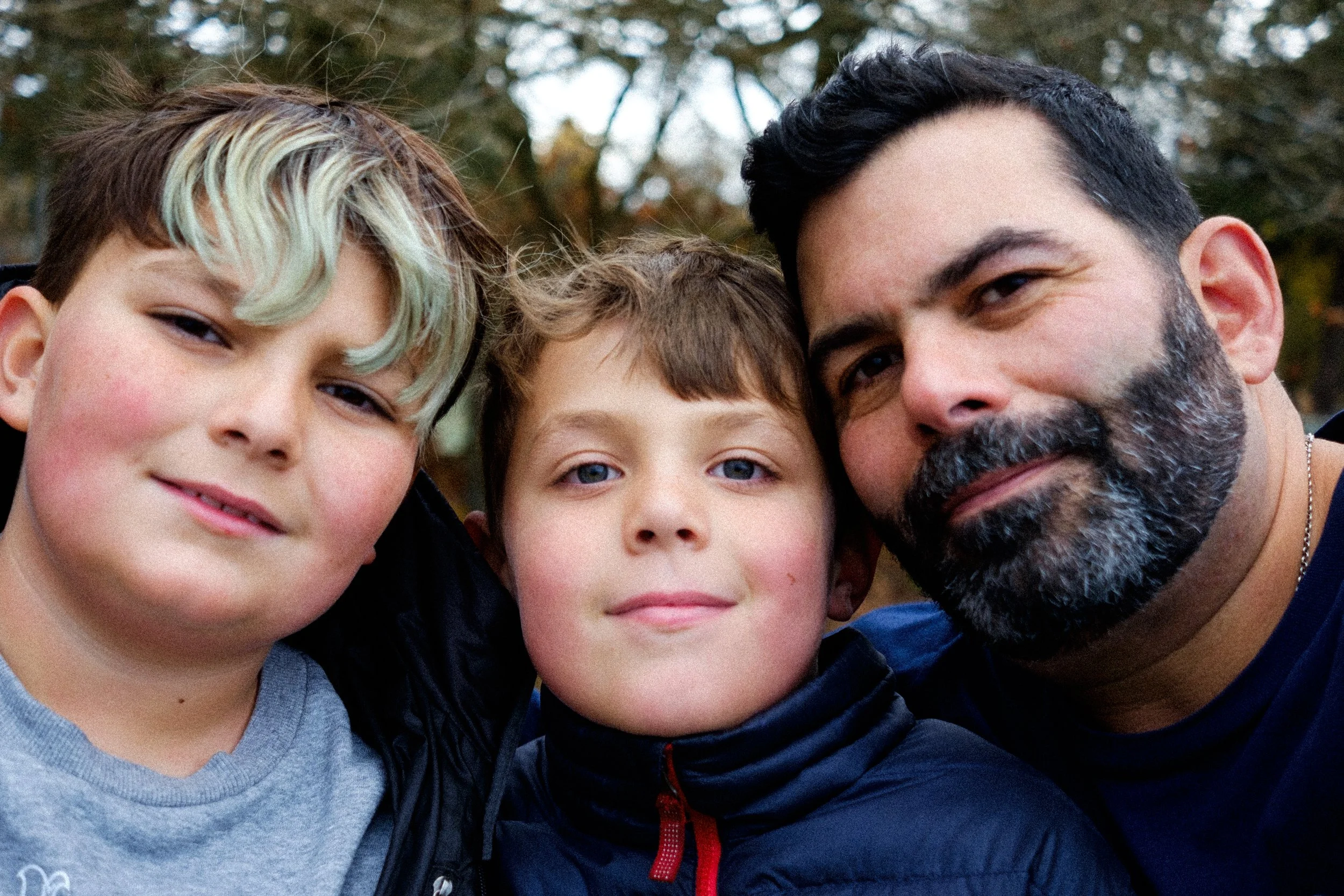 Photographer Ricardo Gotla cheek to cheek with his two sons outdoors